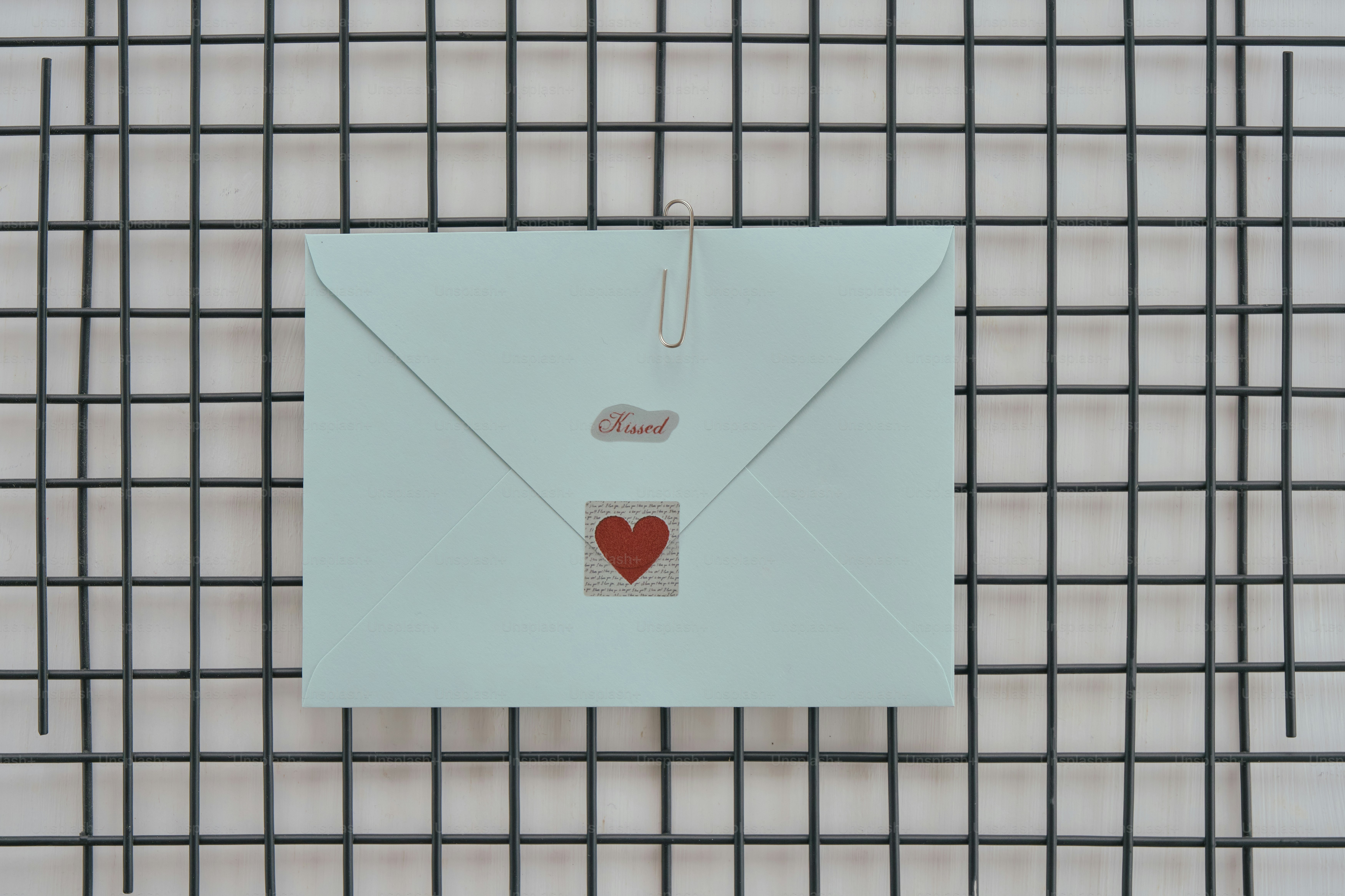 Hellblauer Umschlag mit rotem Herzaufkleber auf dem Raster