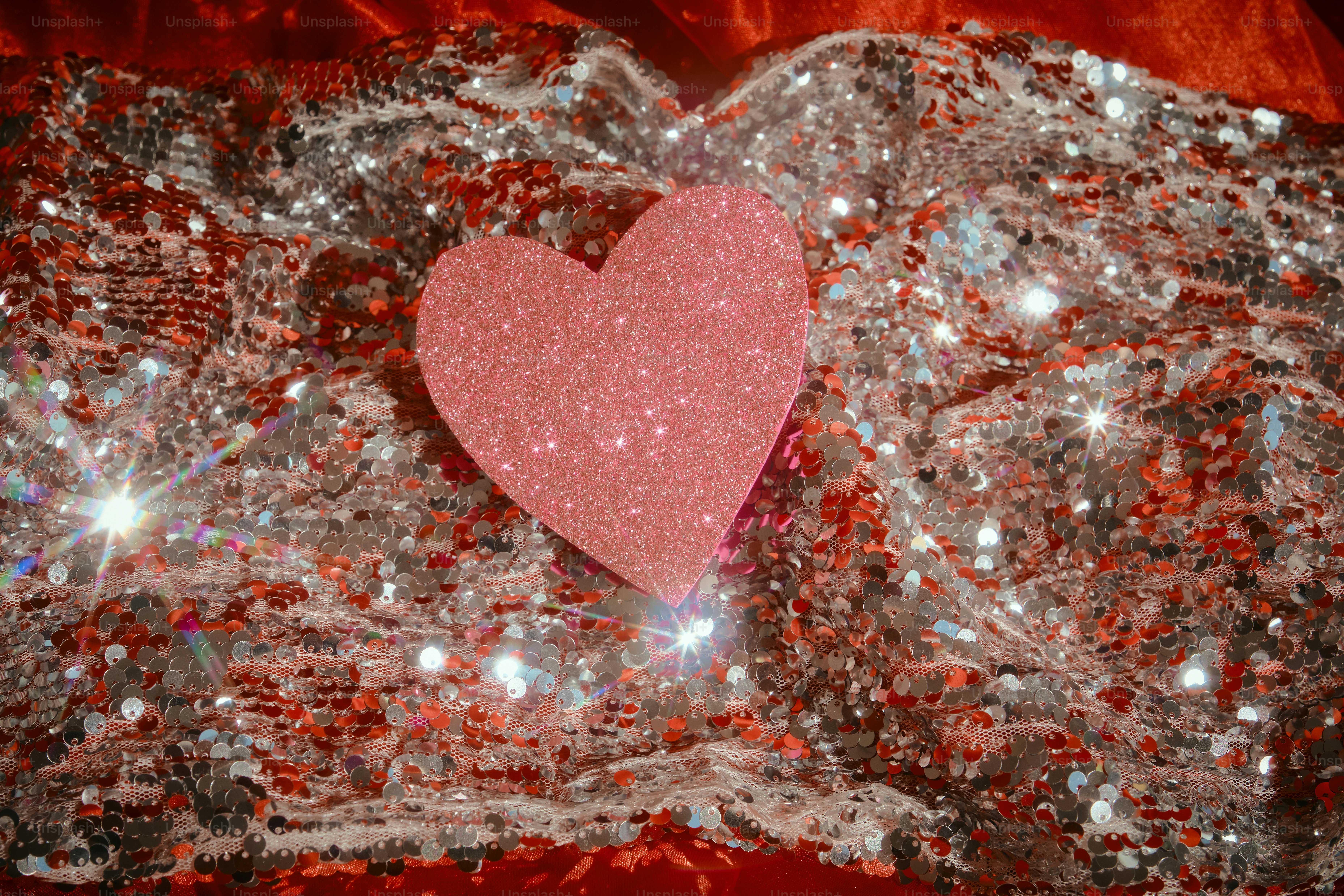 Rosa Glitzerherz auf einem funkelnden roten und silbernen Hintergrund