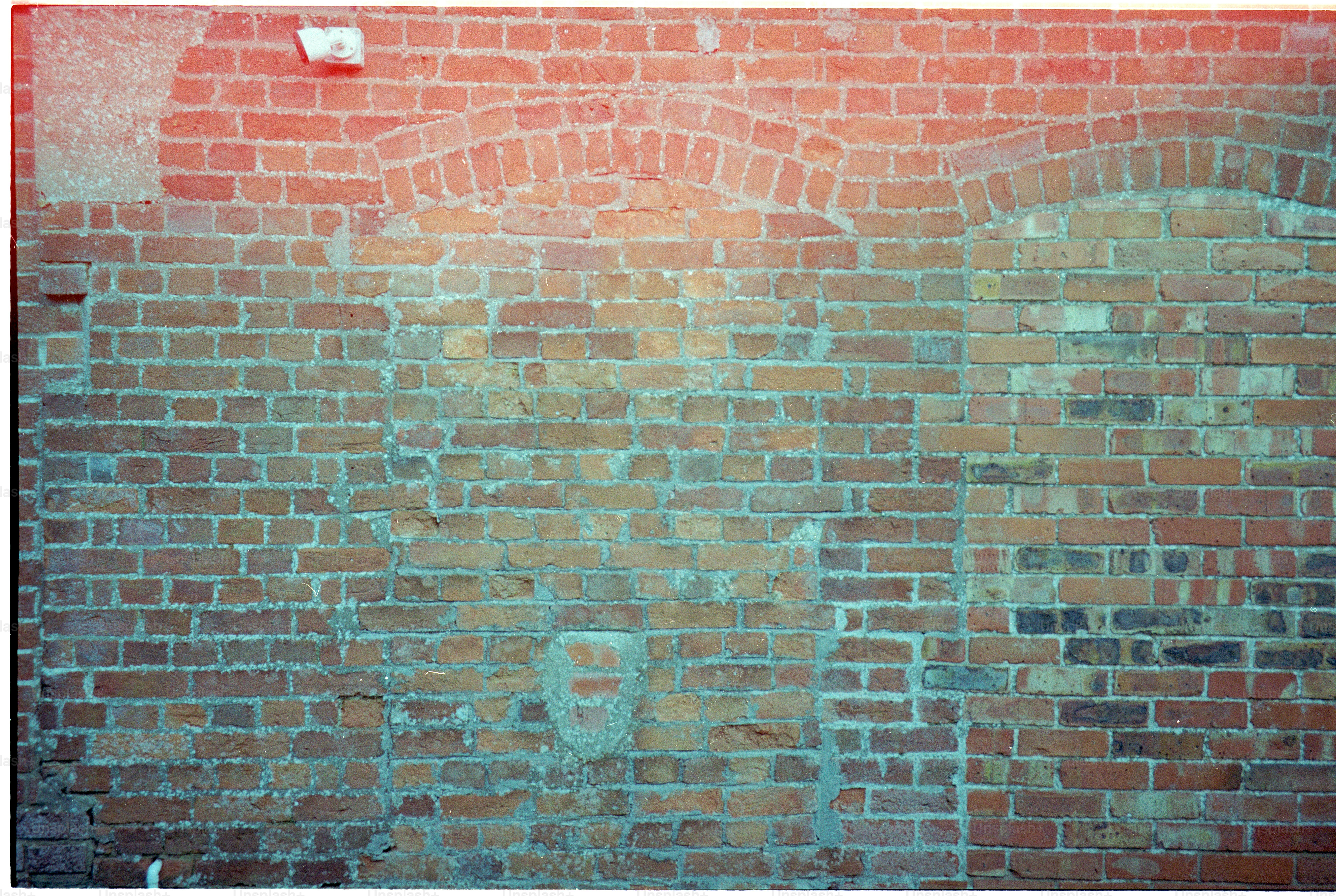 Weathered red brick wall with arched patterns.