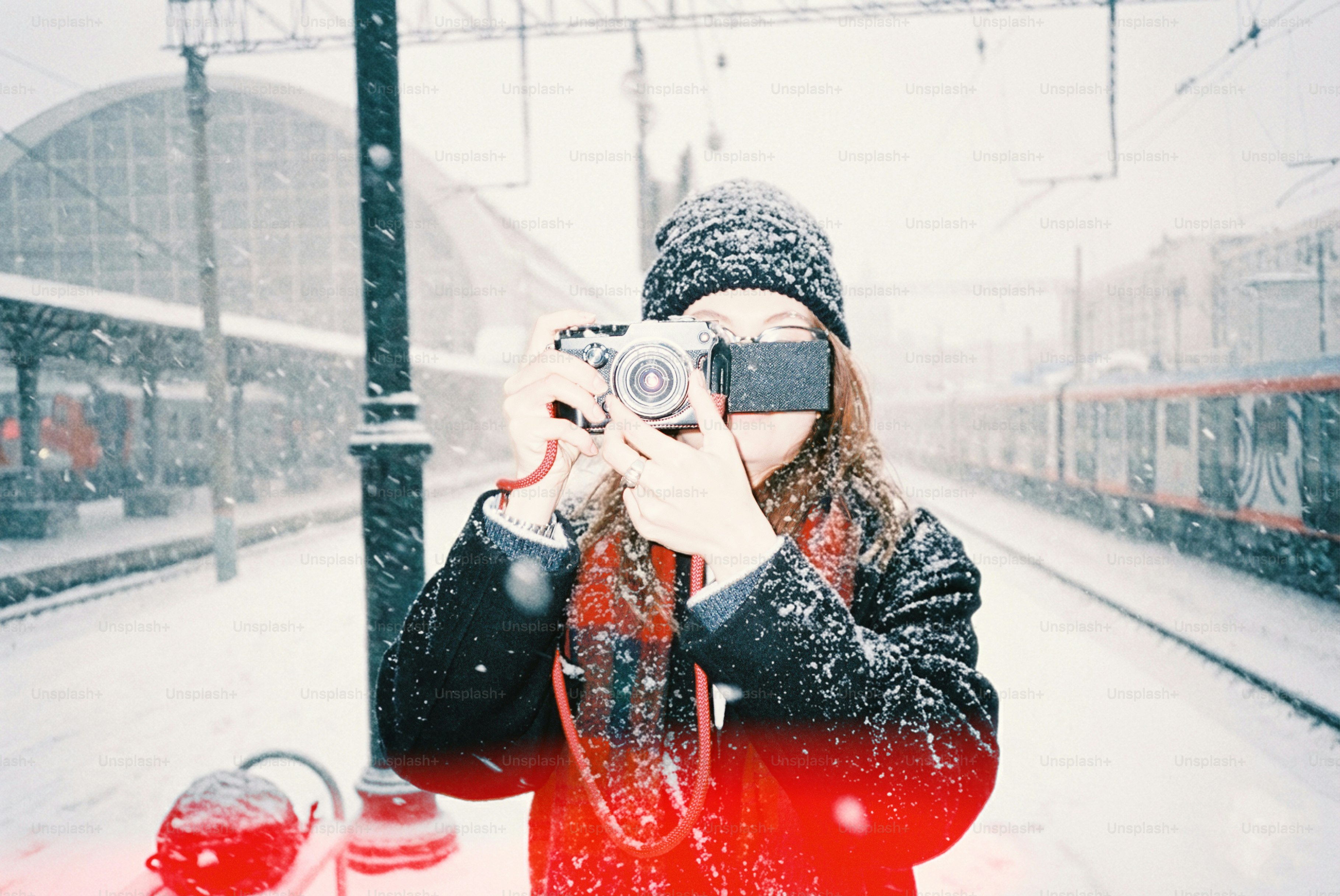 Woman taking a picture in a snowy train station.
