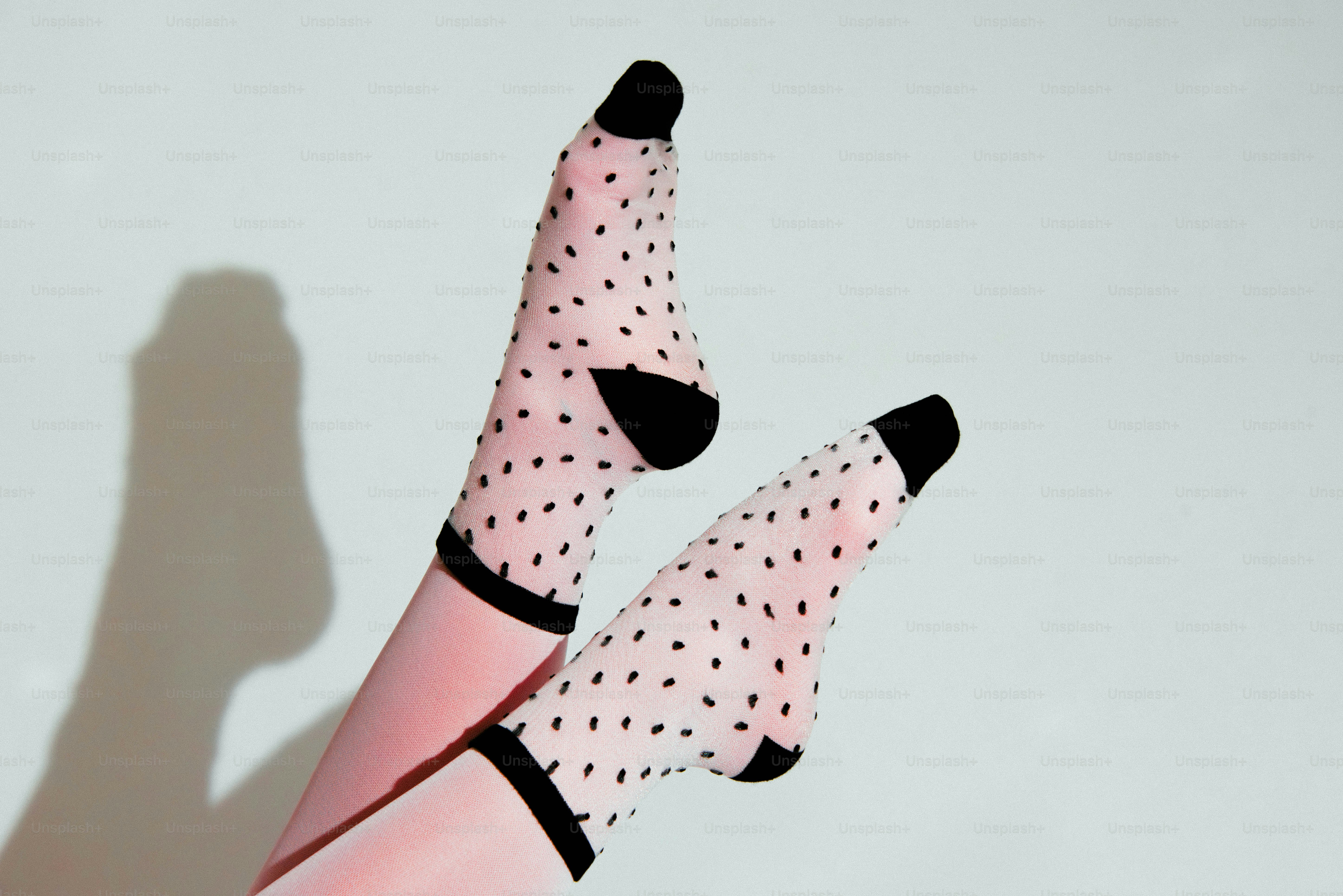 Deux jambes portant des chaussettes roses à pois noirs