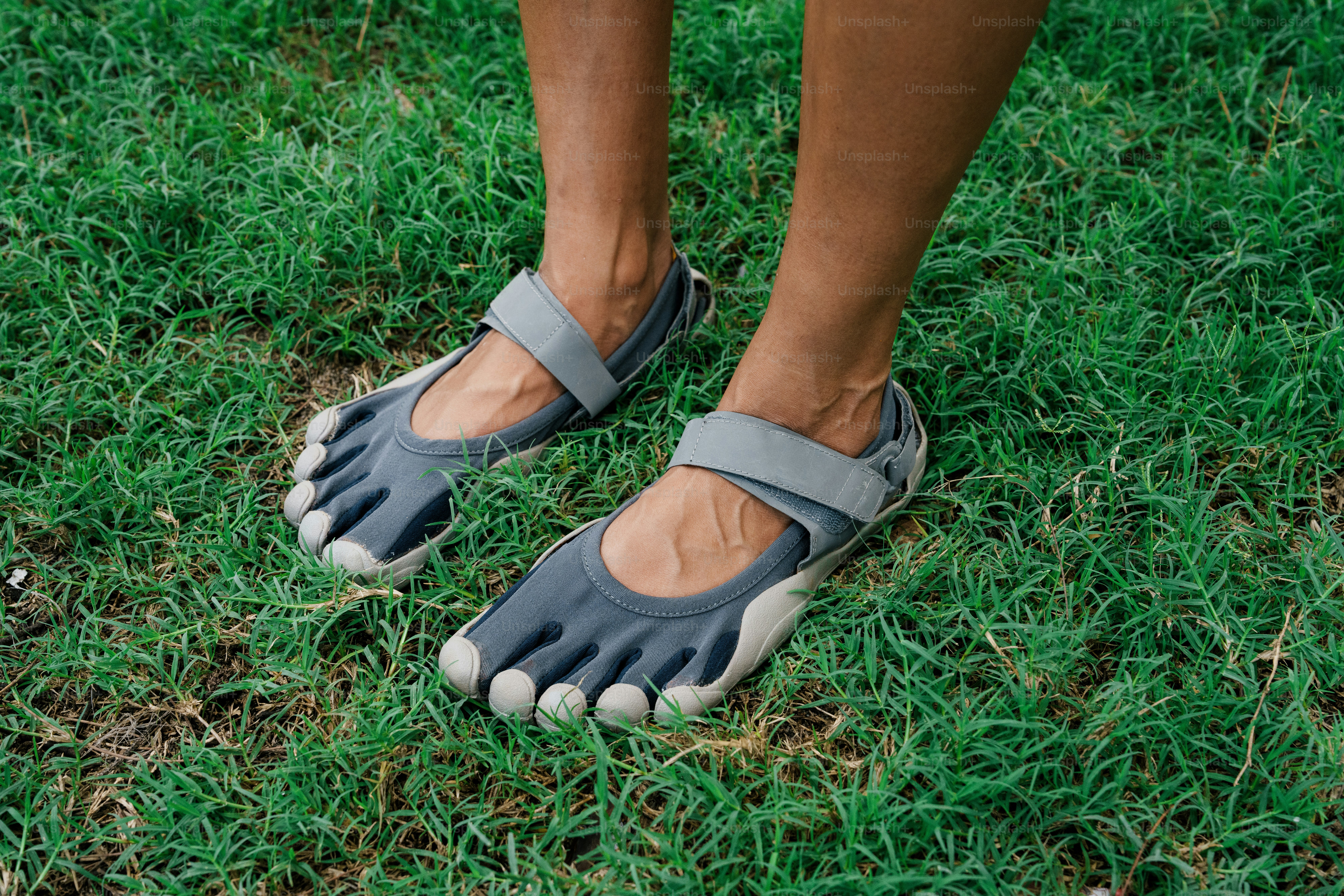 Feet wearing minimalist shoes on green grass