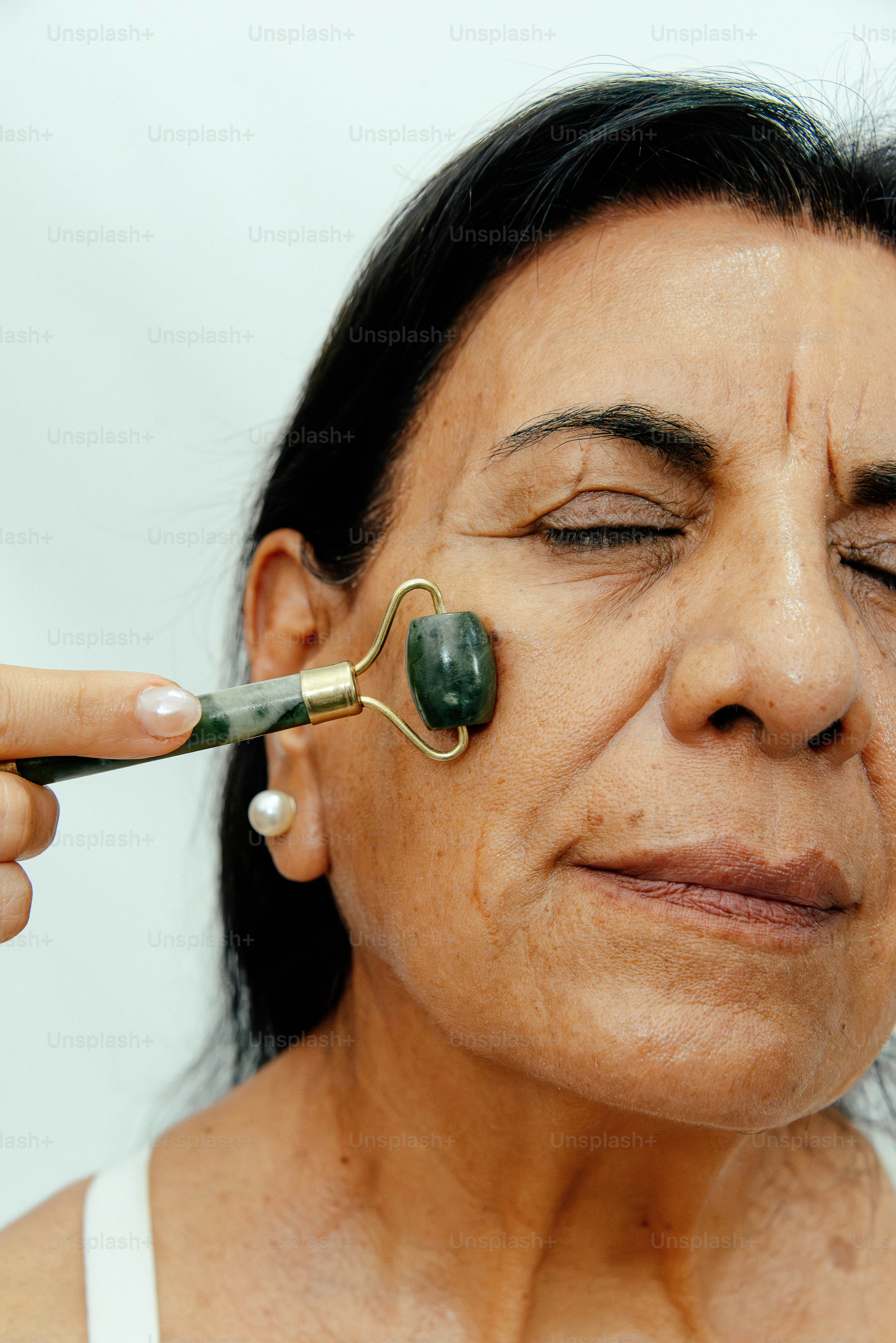 Frau benutzt eine Jaderolle im Gesicht