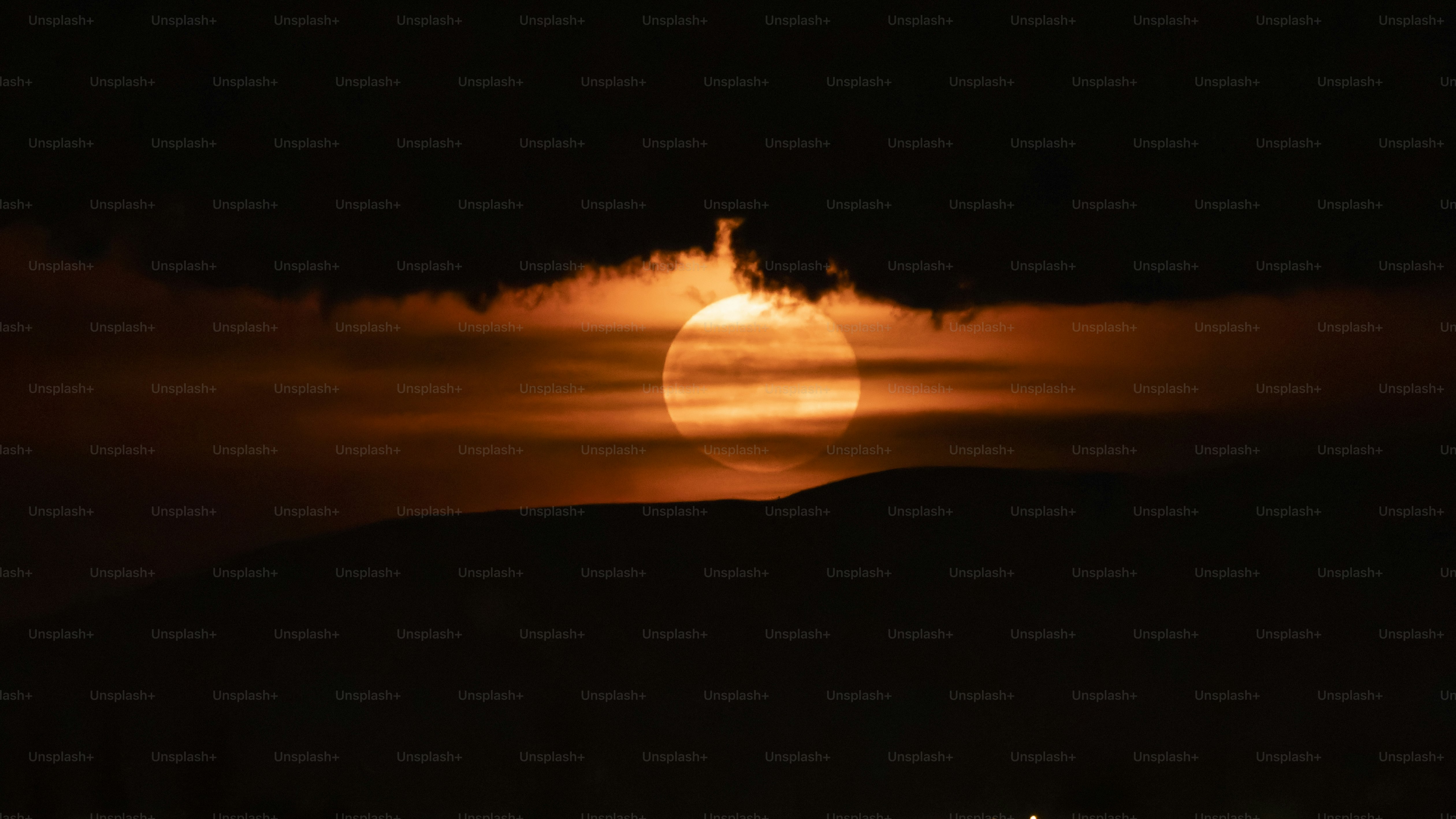 Fiery sun peeking through dark, ominous clouds at dusk