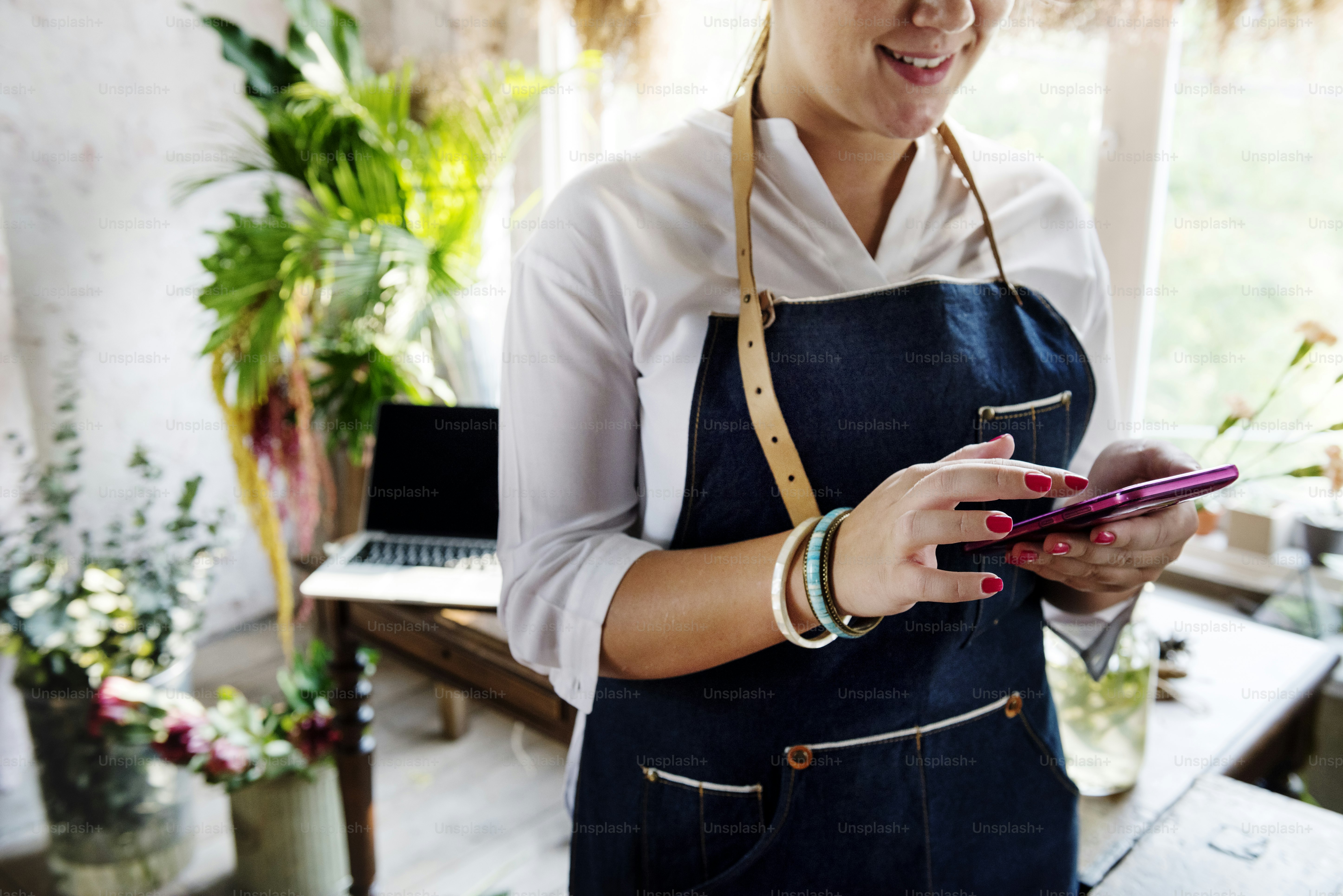 Florist woman using mobile phone at flower shop
