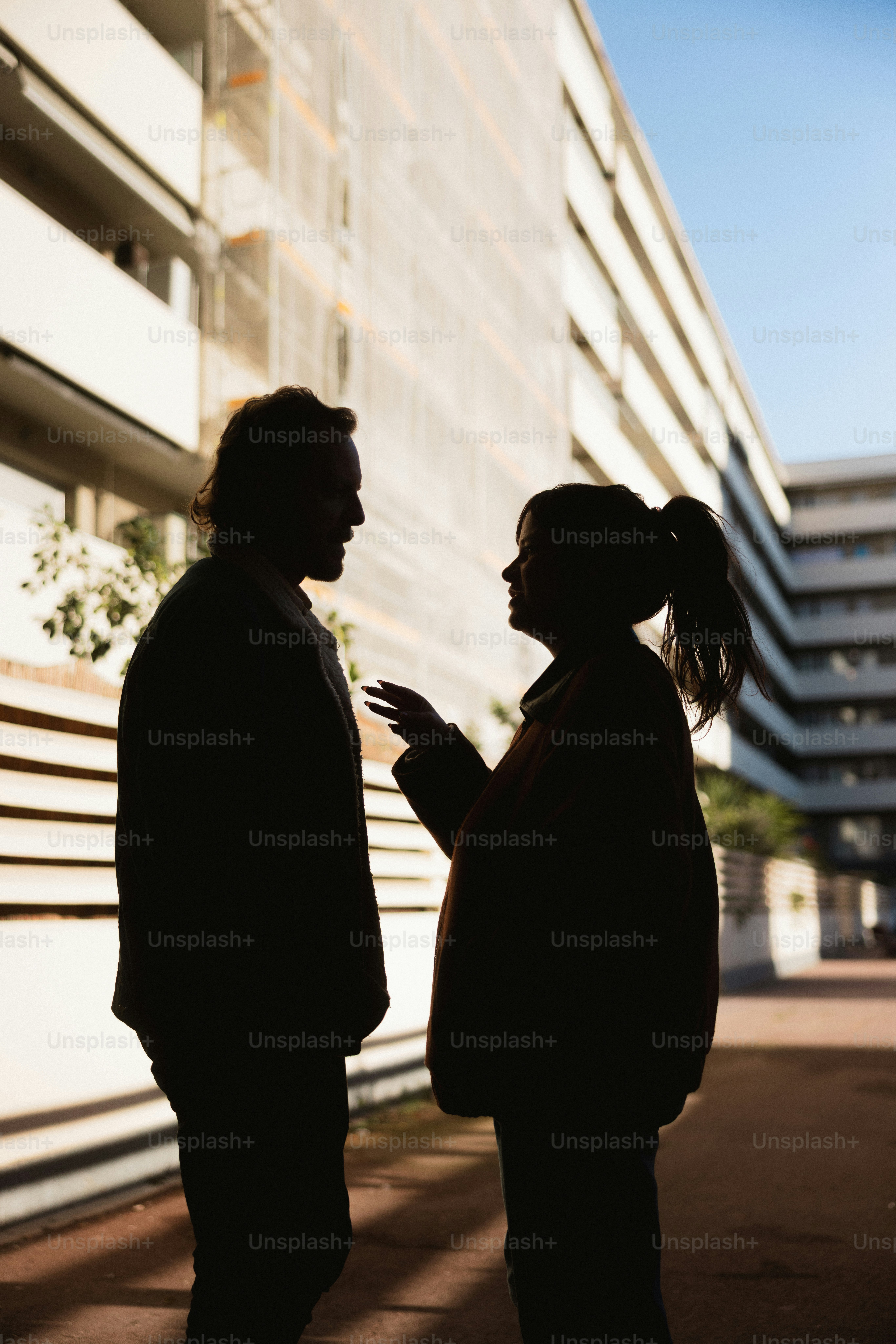 Deux personnes silhouettées contre un bâtiment