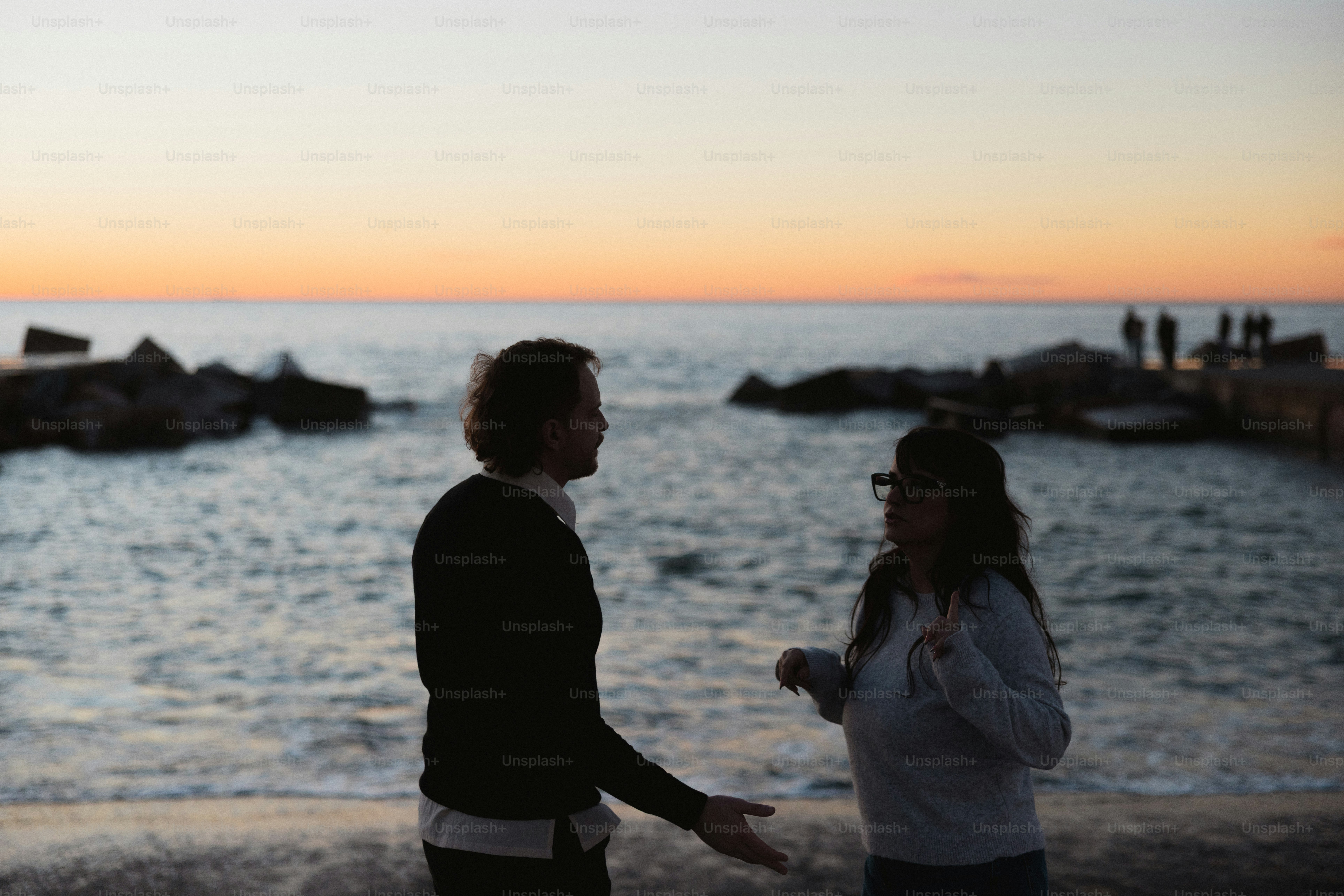 Deux personnes qui parlent sur une plage au coucher du soleil