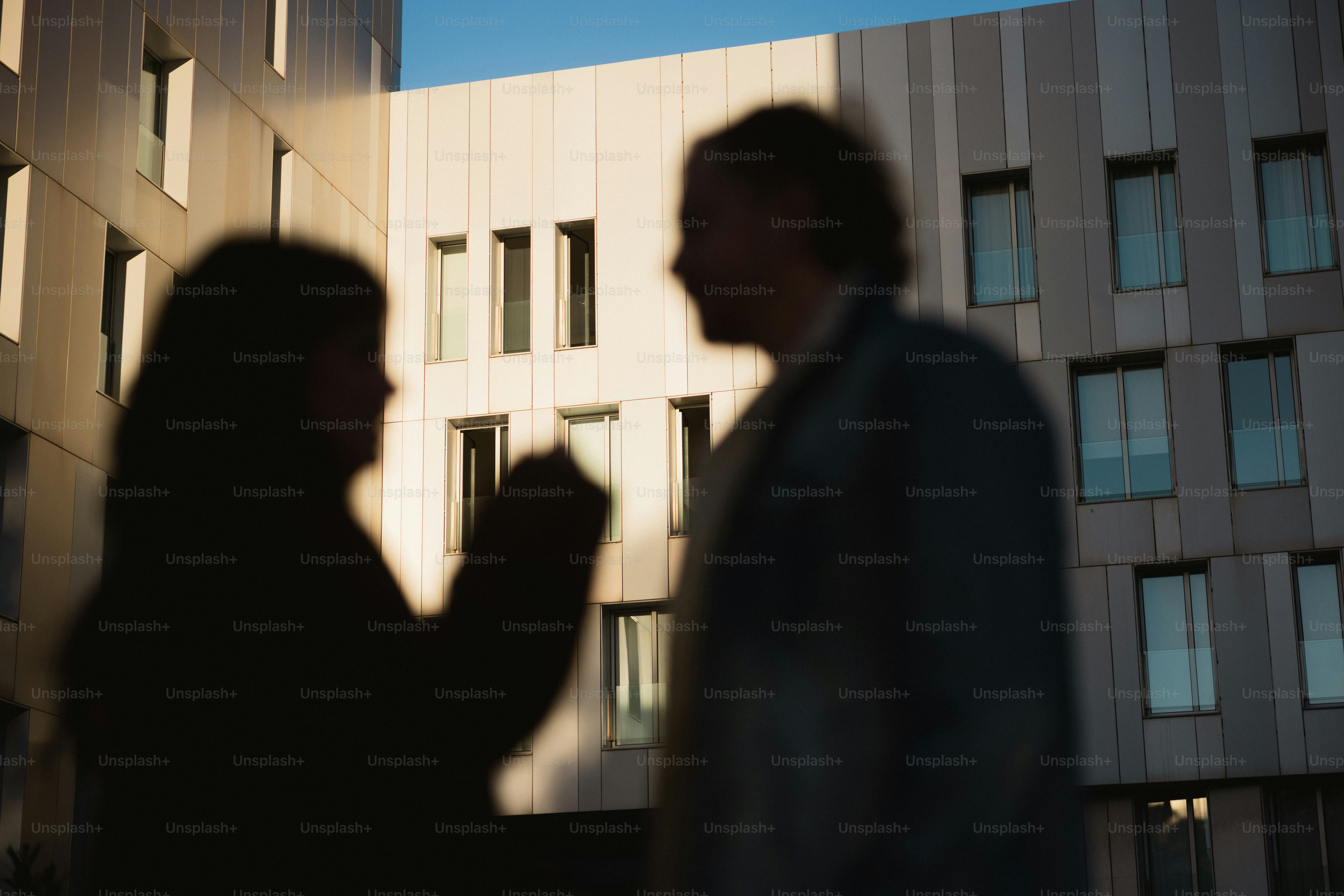 Two people silhouetted against a modern building