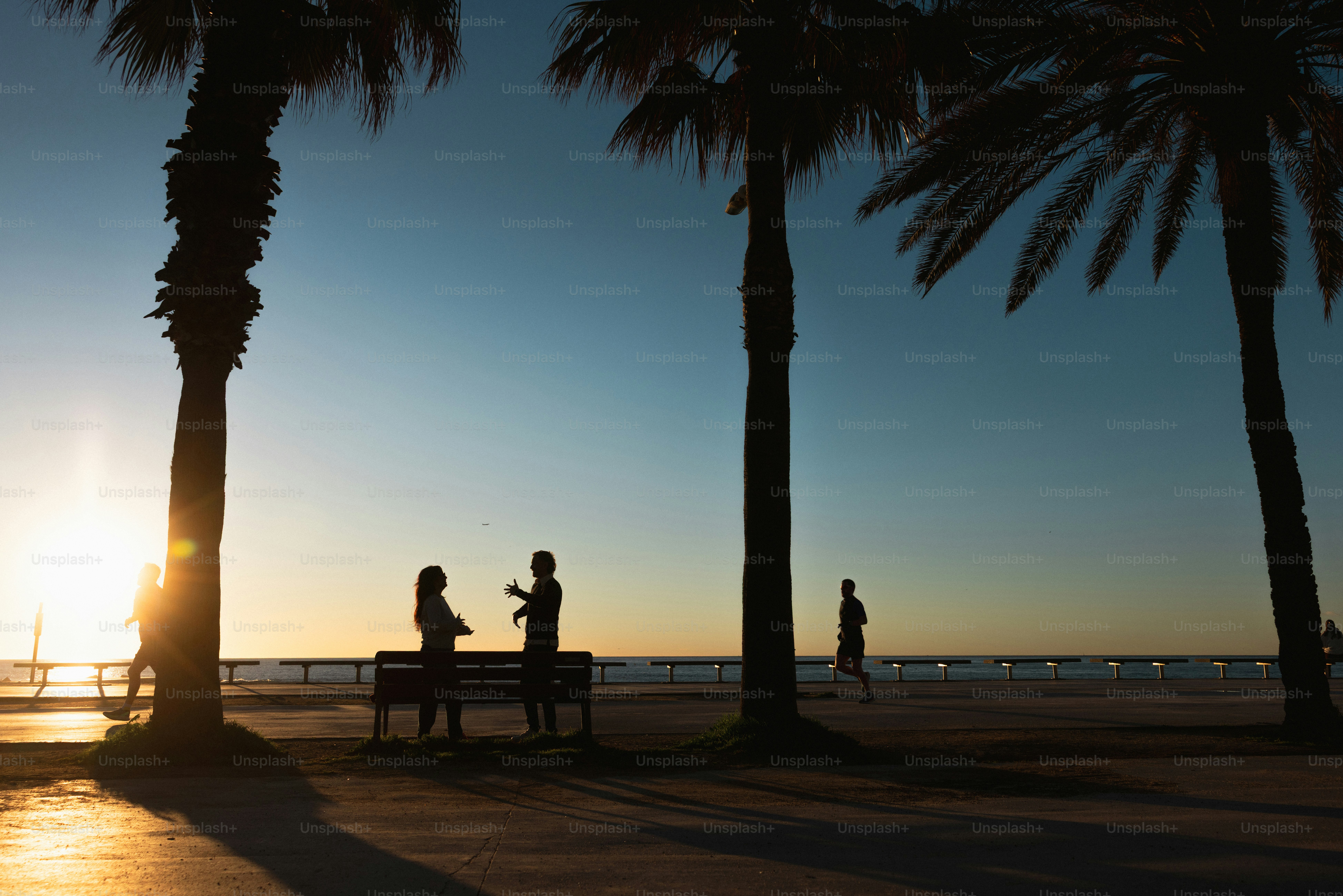 Des silhouettes de personnes sur une promenade au coucher du soleil.