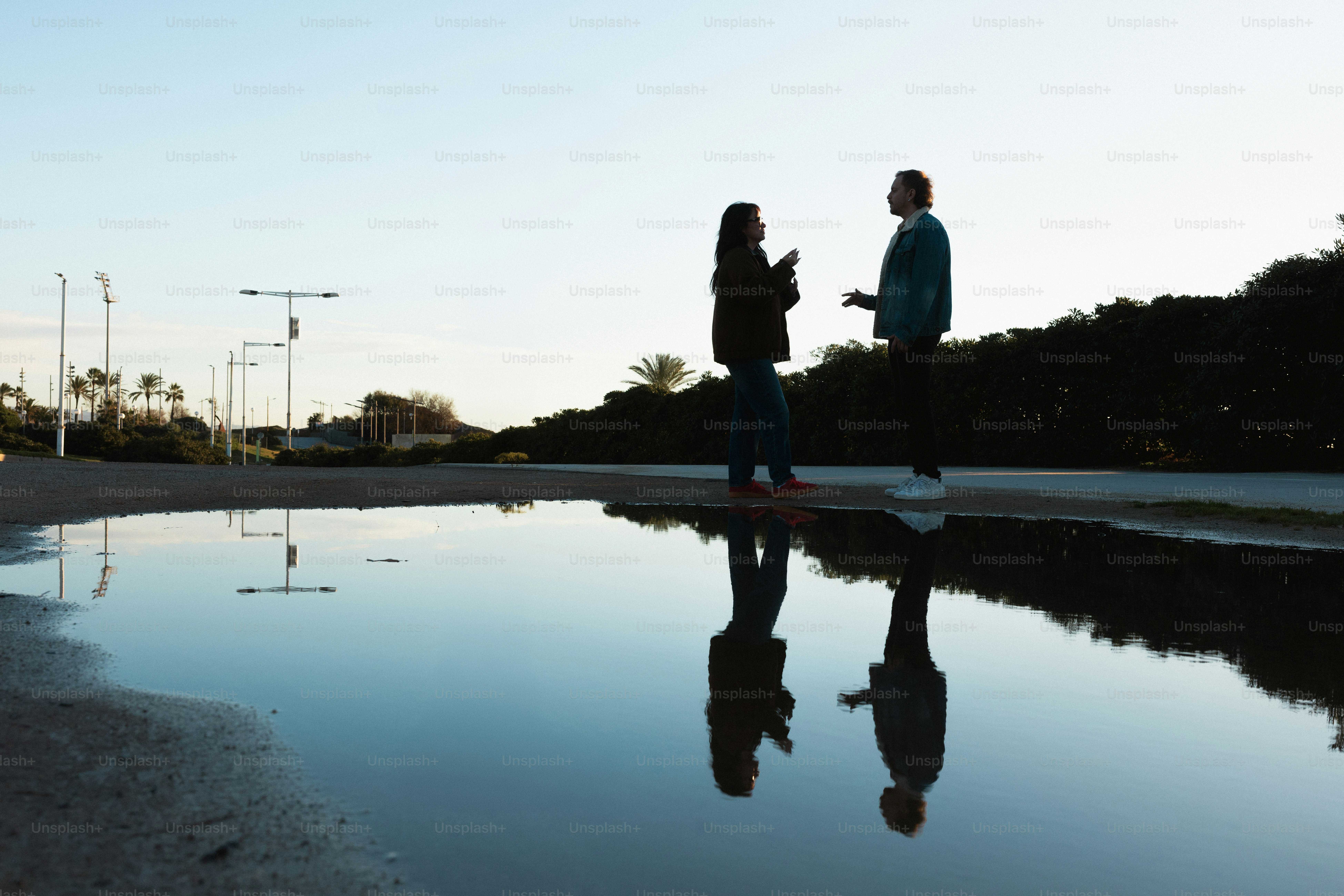 Deux personnes parlant reflétées dans une grande flaque d’eau