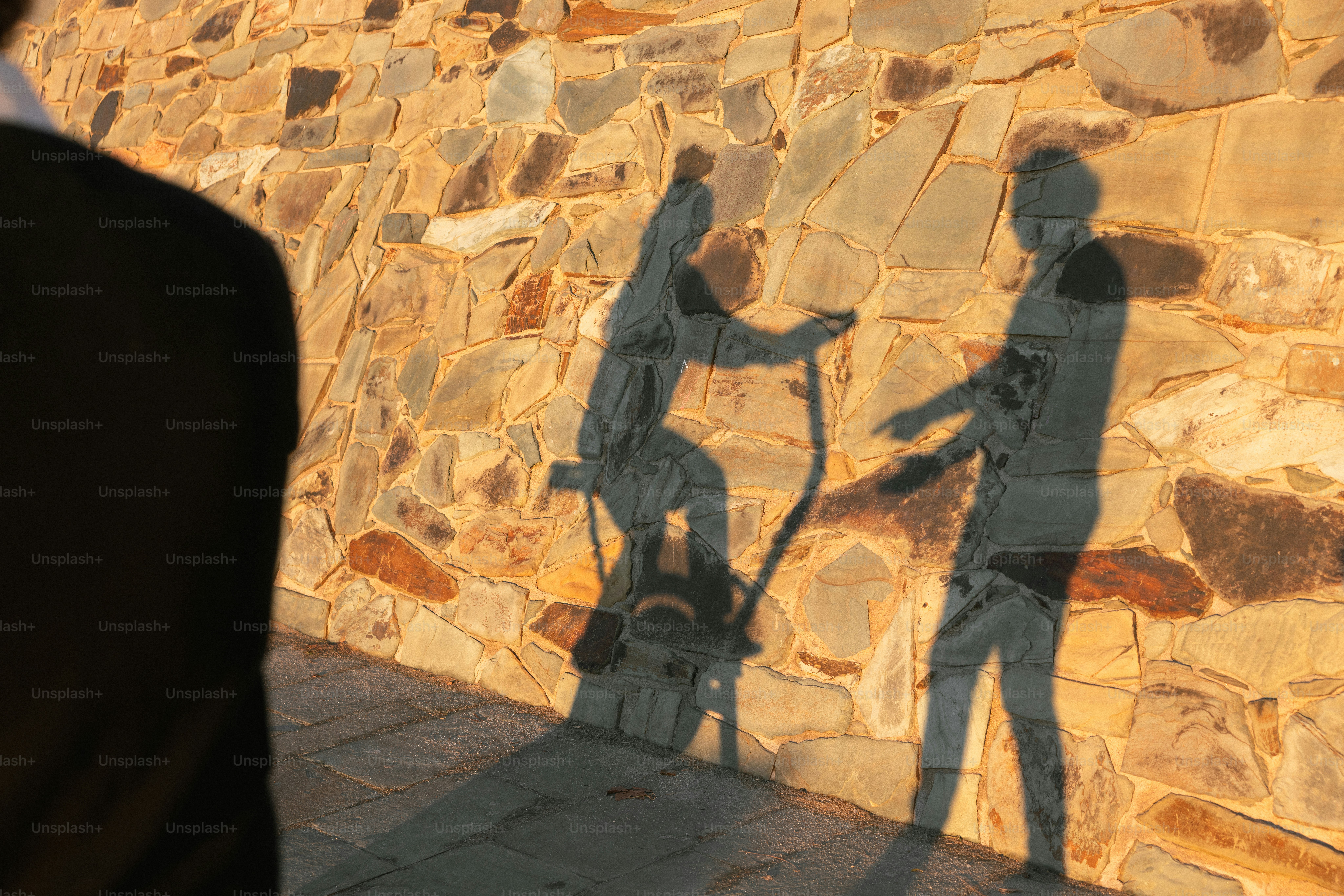 Ombres de personnes sur un mur de pierre