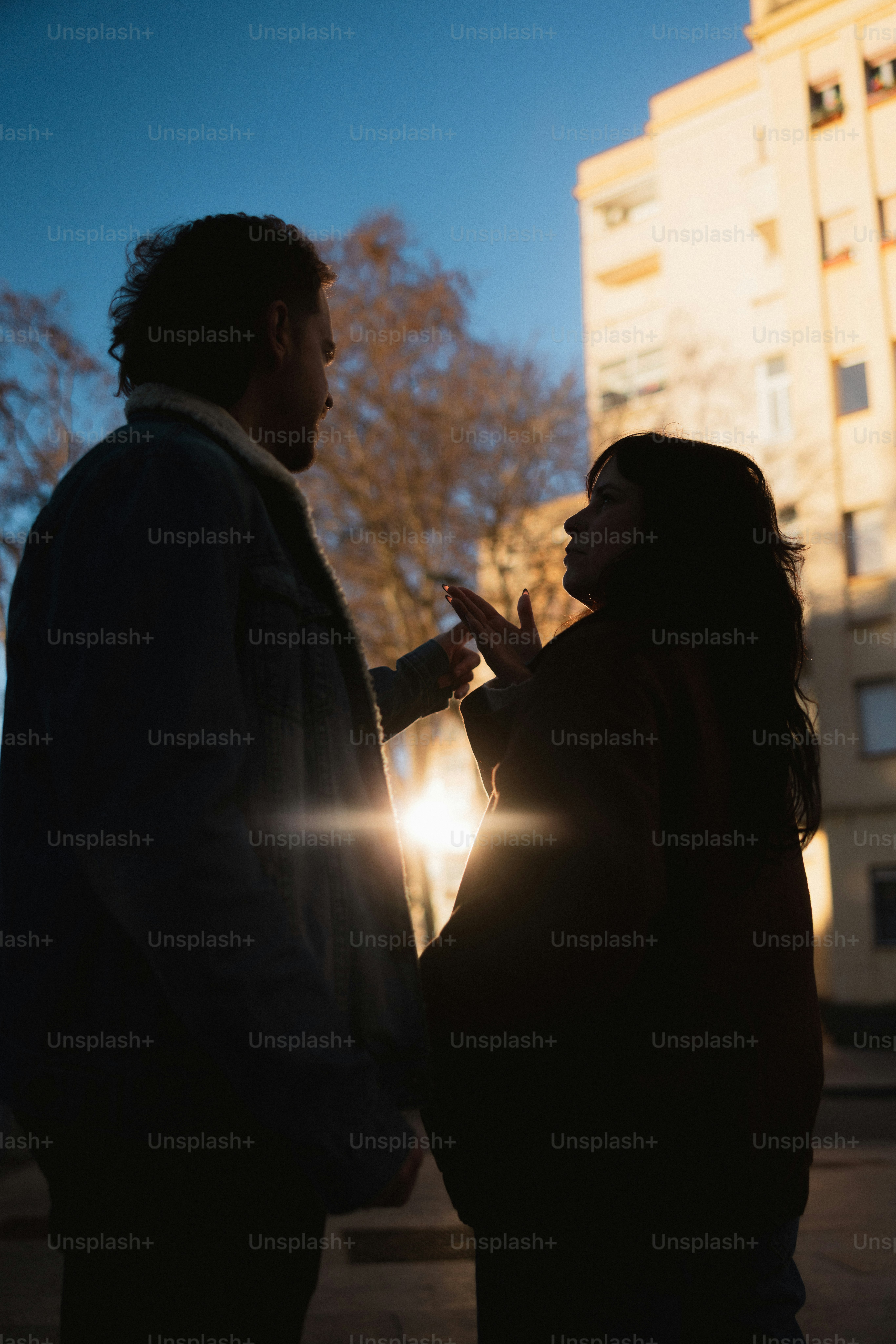 Un couple se découpait contre le soleil et les bâtiments.