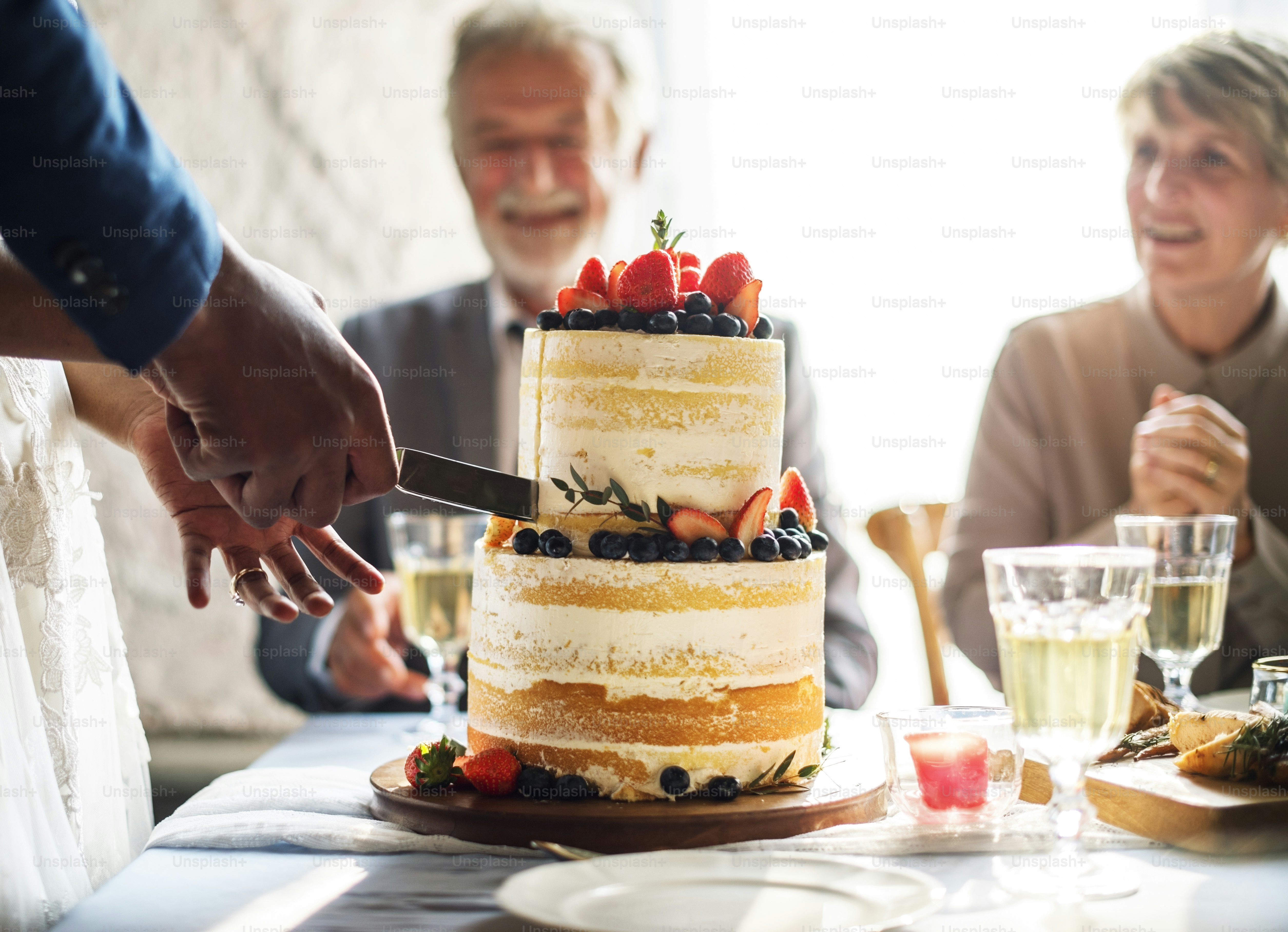 Manos de pareja cortando tarta de boda