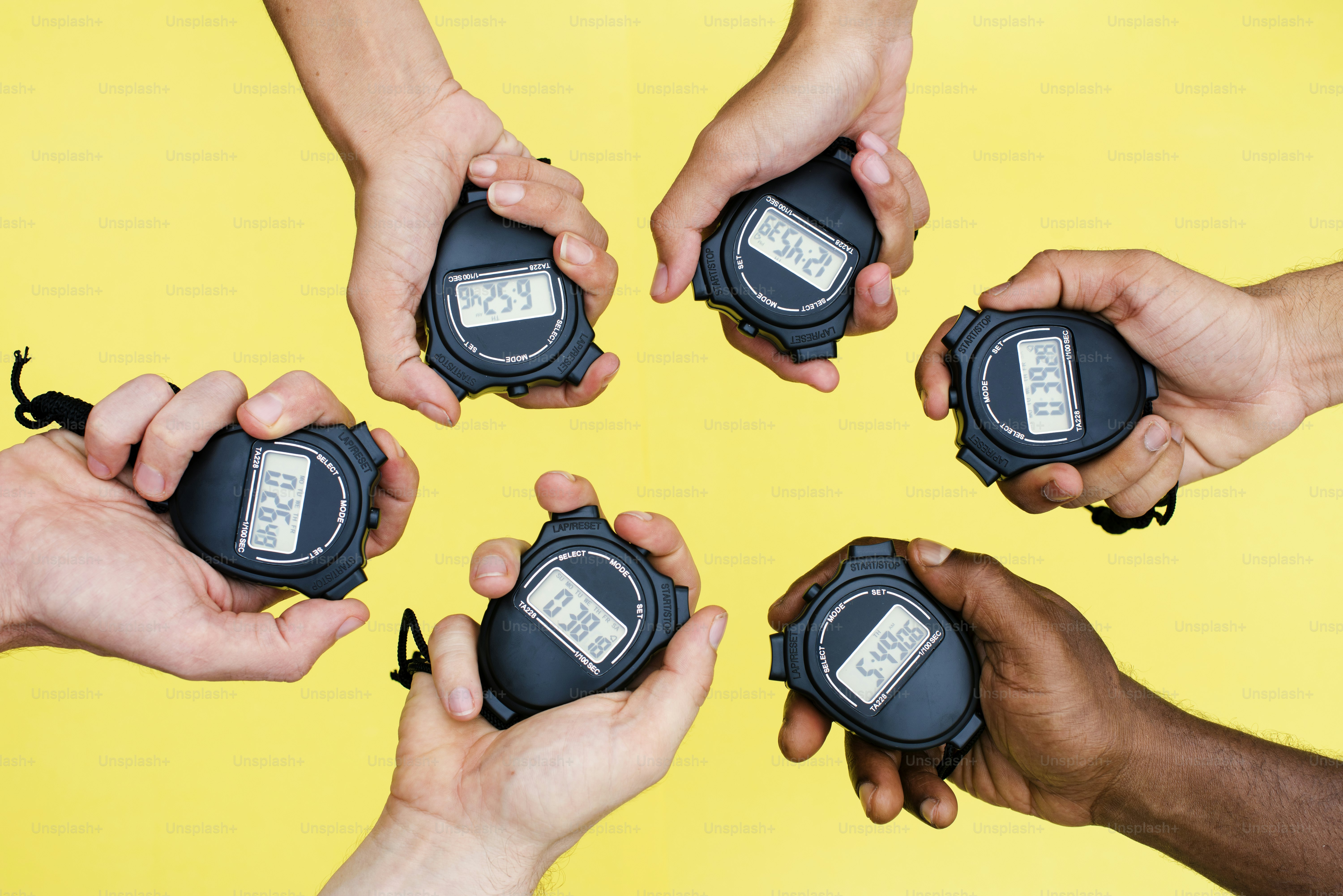 Nahaufnahme von Zeigern, die Stoppuhren mit gelbem Hintergrund halten