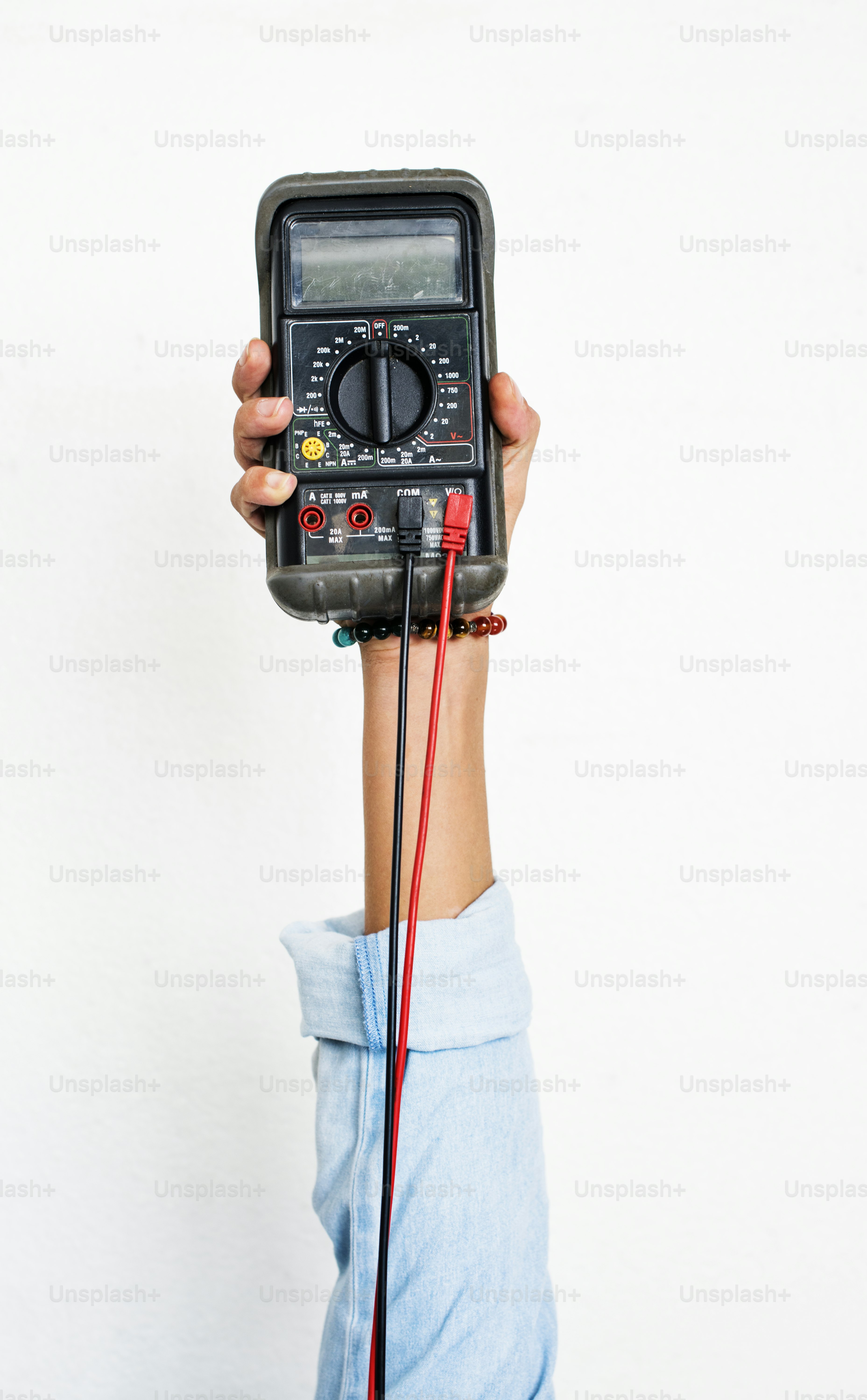 Hand holding electrics measure multimeter isolated on white