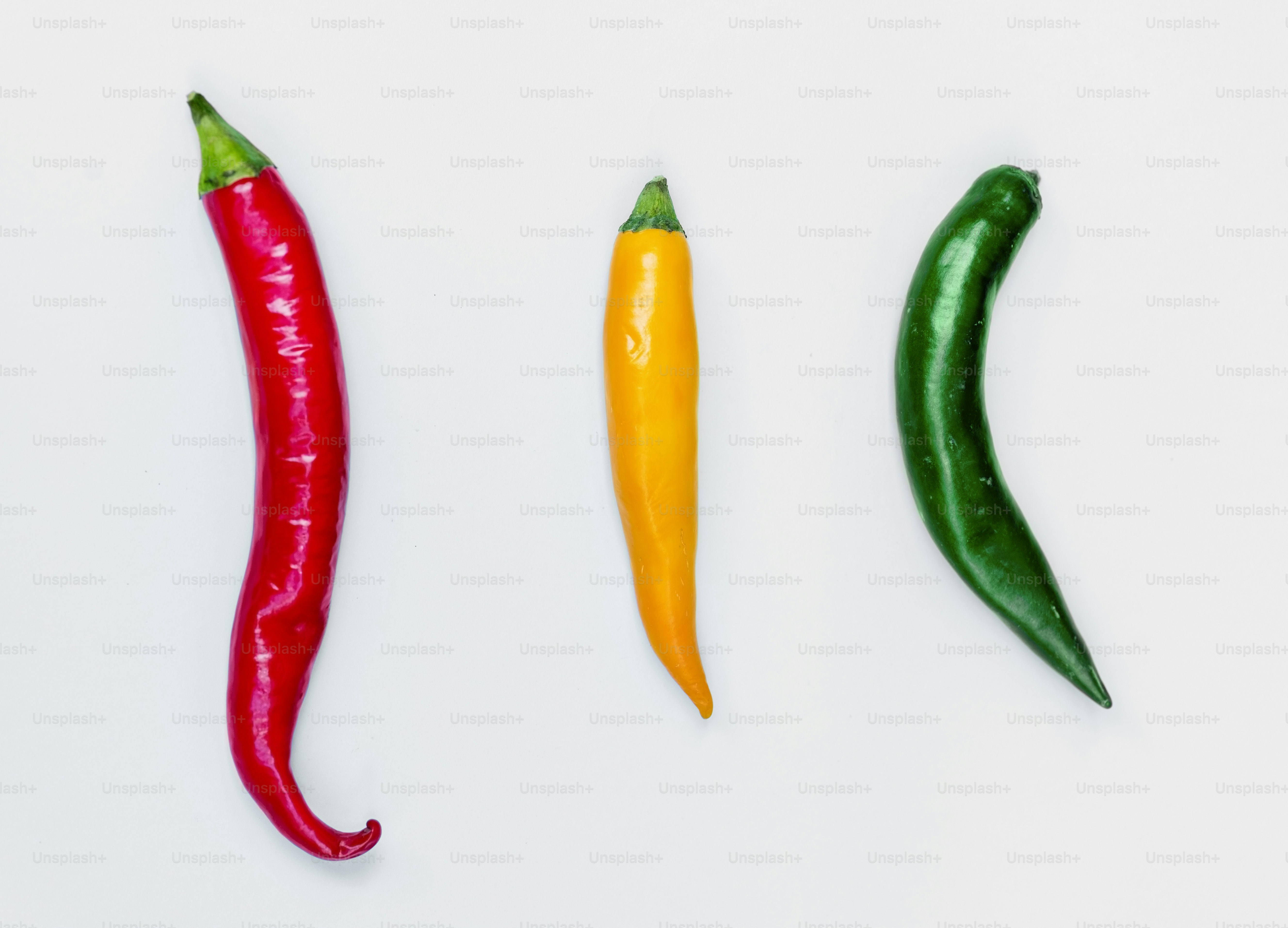 Aerial view of fresh red green yellow chili peppers on white background
