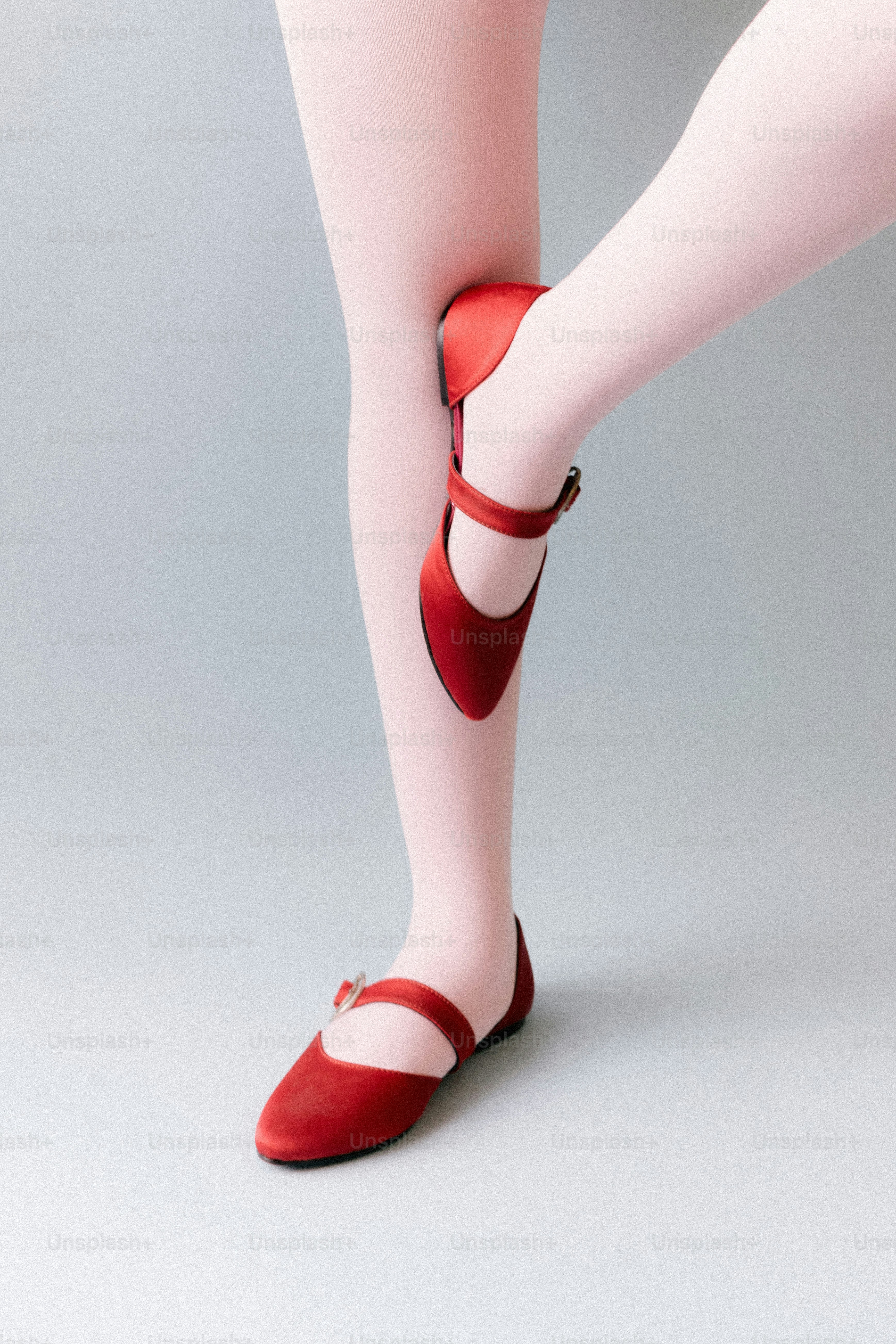Die Beine einer Tänzerin in rosa Strumpfhosen und roten Ballettschuhen