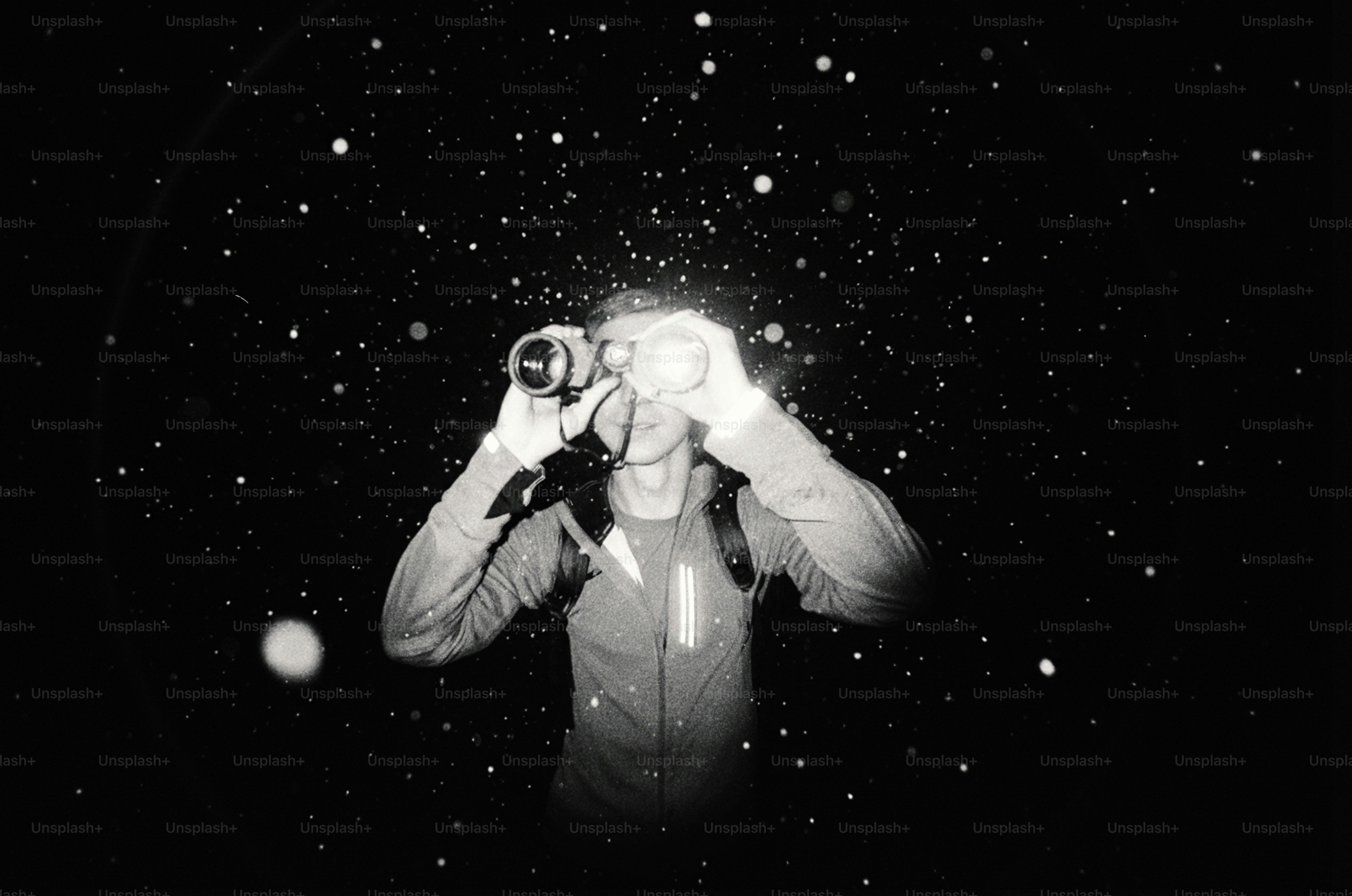 Person looking through binoculars at night with light specks