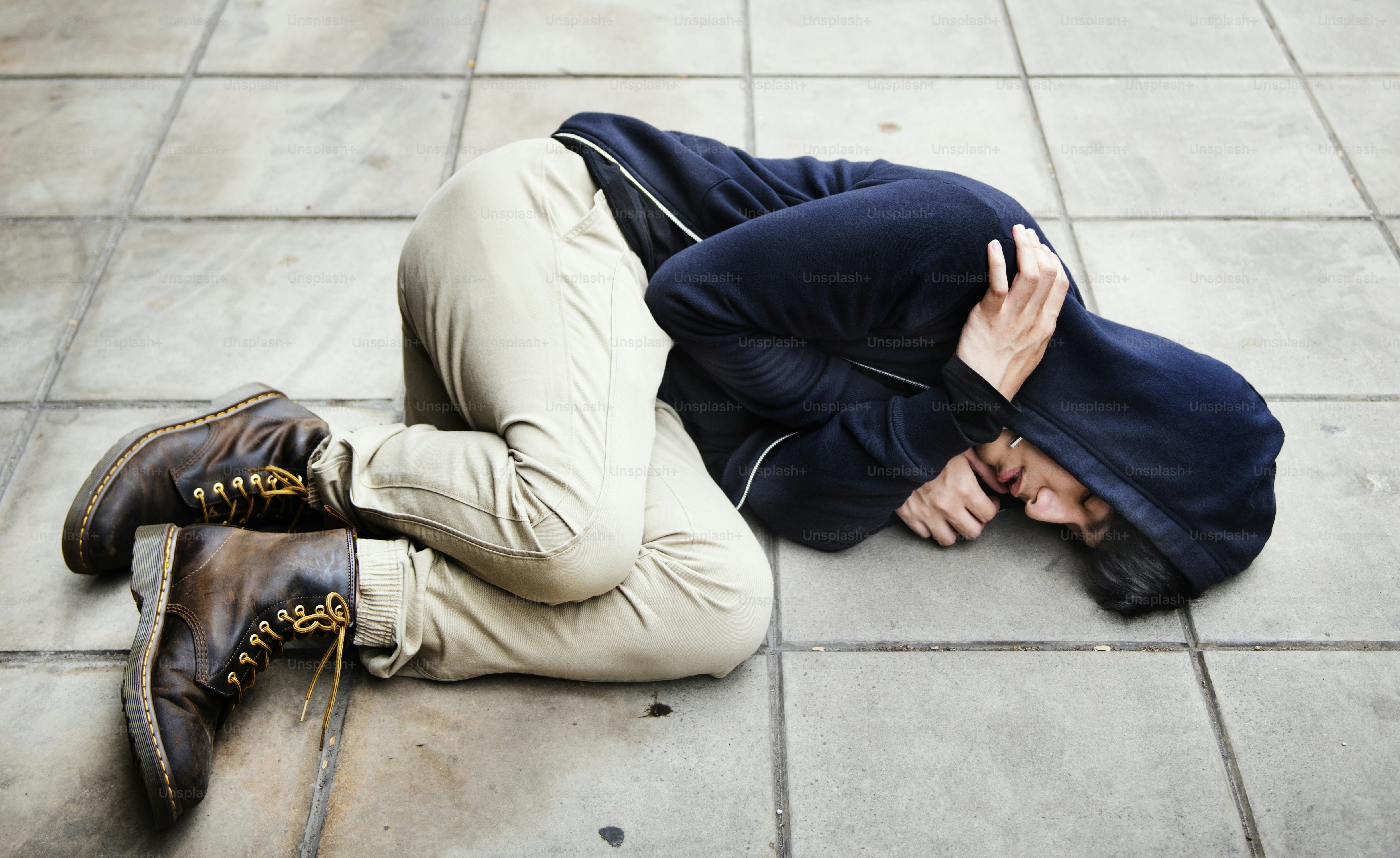 Guy in a hoodie fetal position on the floor