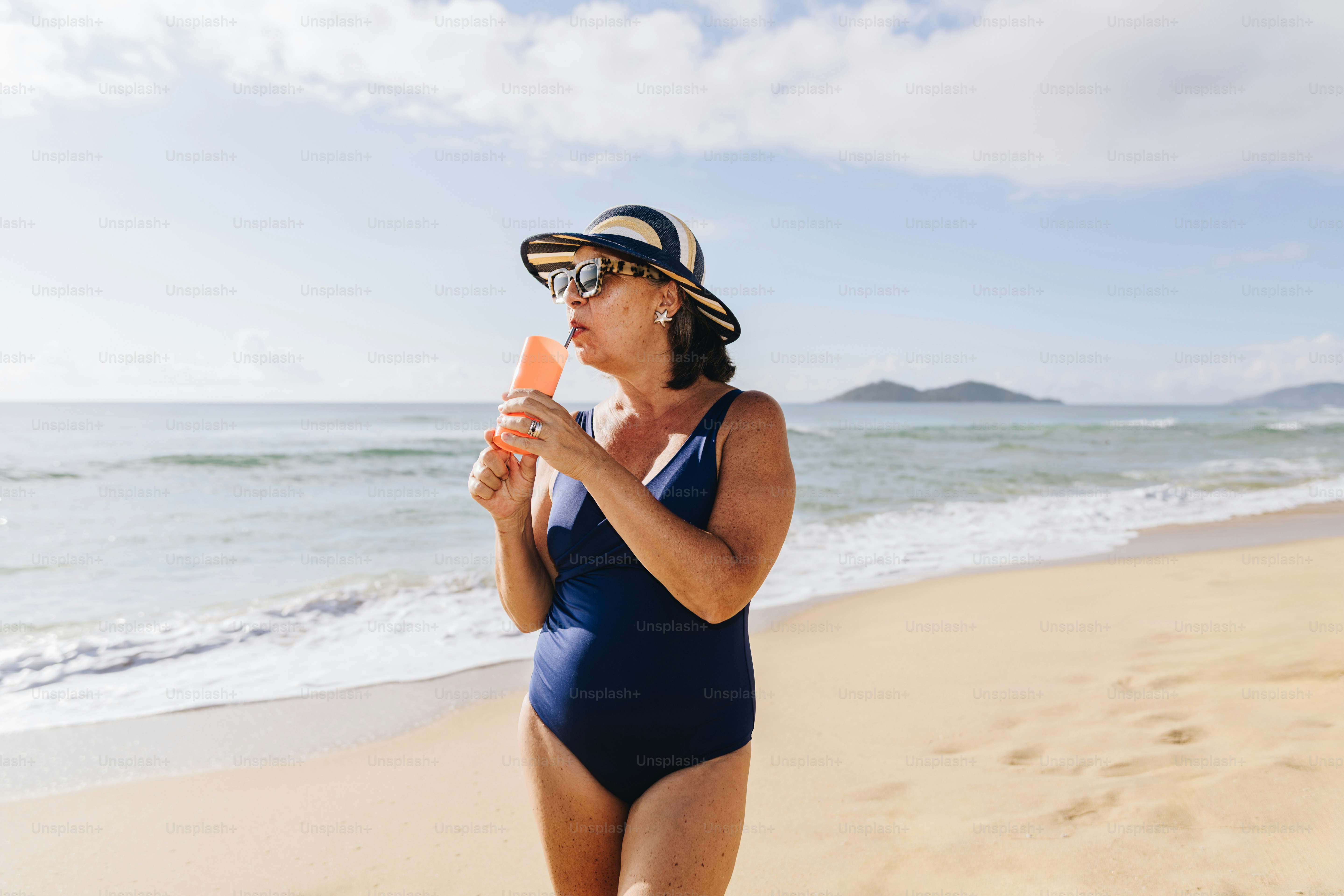Woman in swimsuit eating popsicle on beach