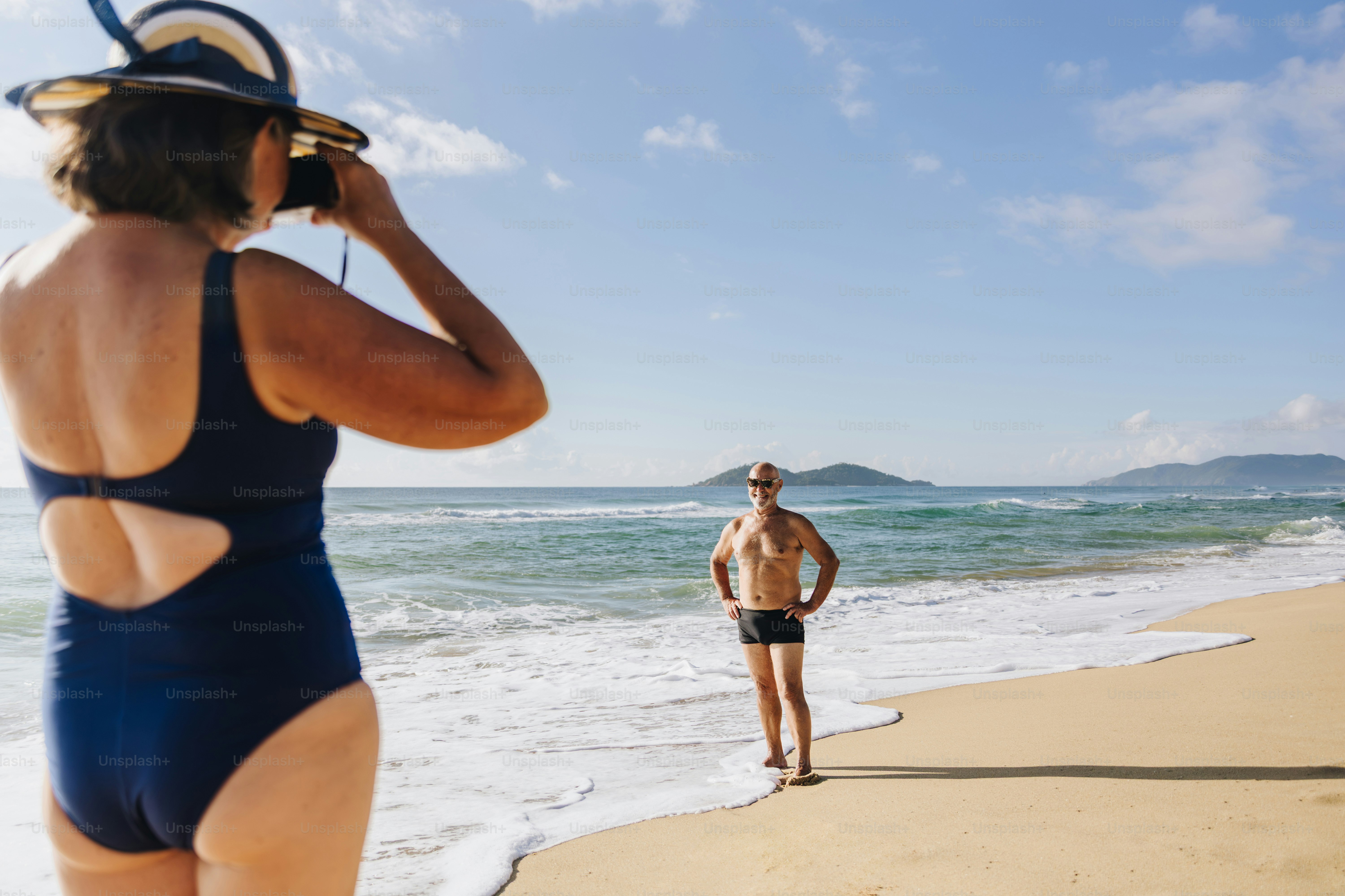 Woman photographs man on a sunny beach