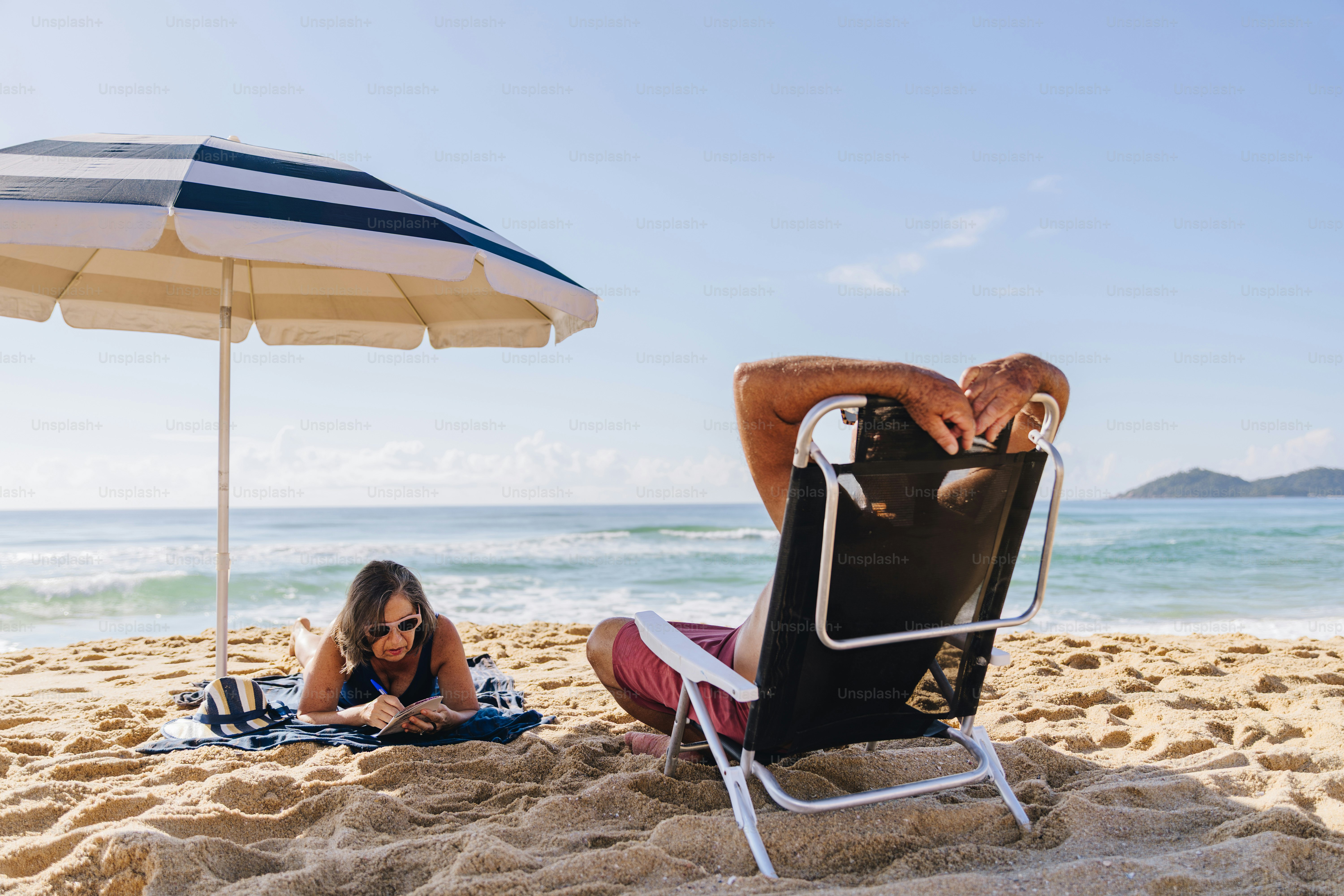 Couple relaxing on a sunny beach under an umbrella.