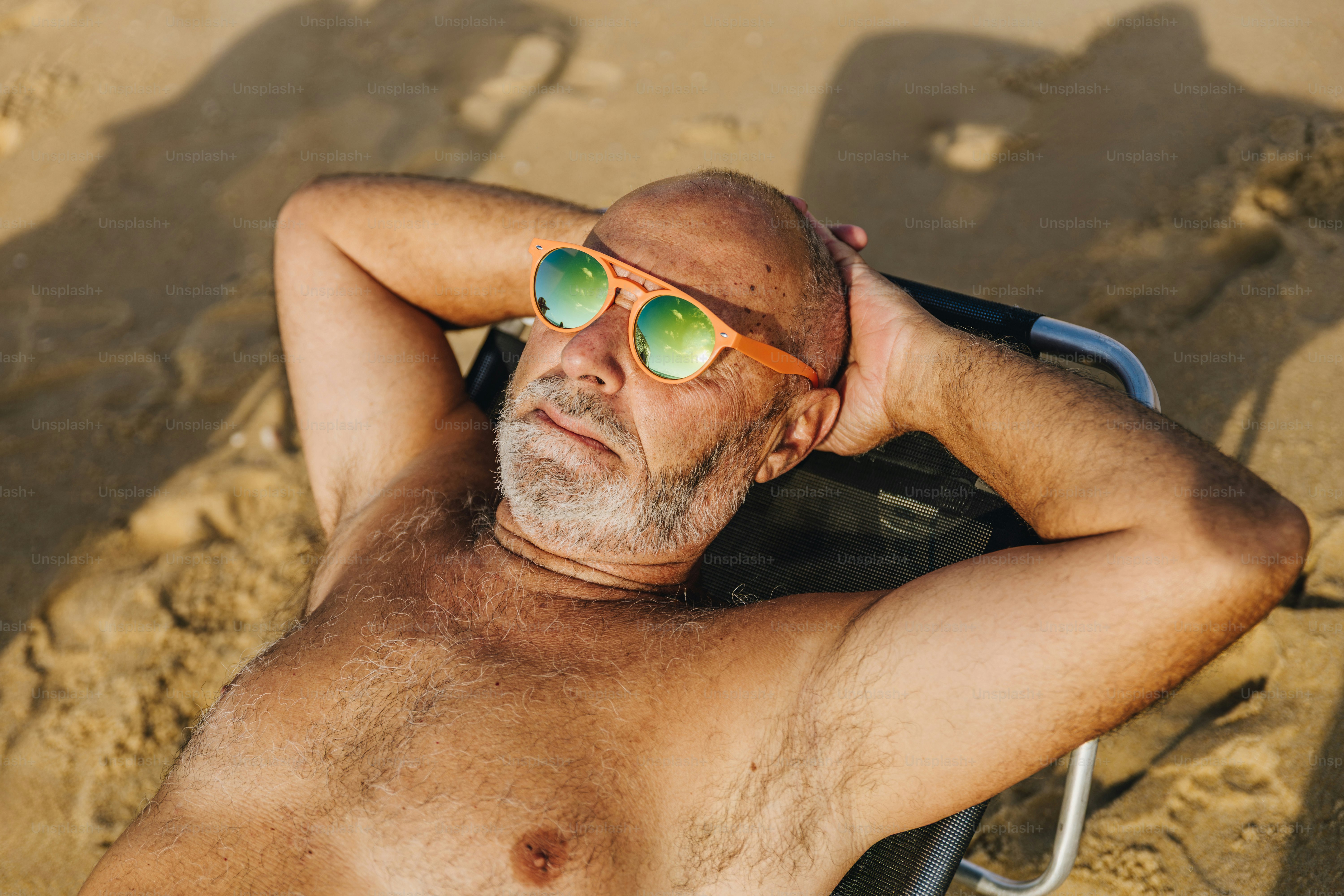 Man in bucket hat on sunny beach with umbrella photo – Beach Image on ...