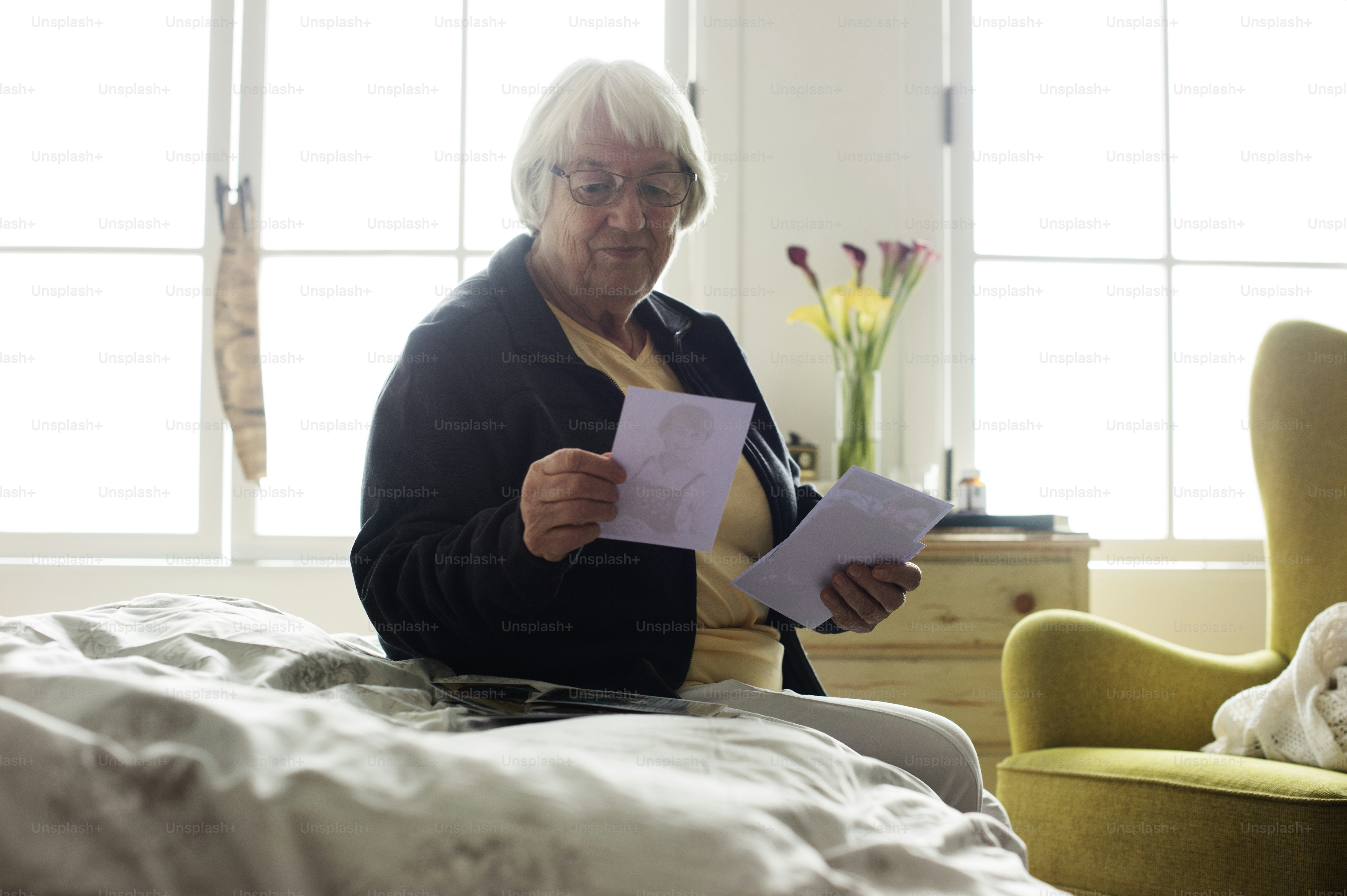 Senior woman sitting on the bed and looking at photos
