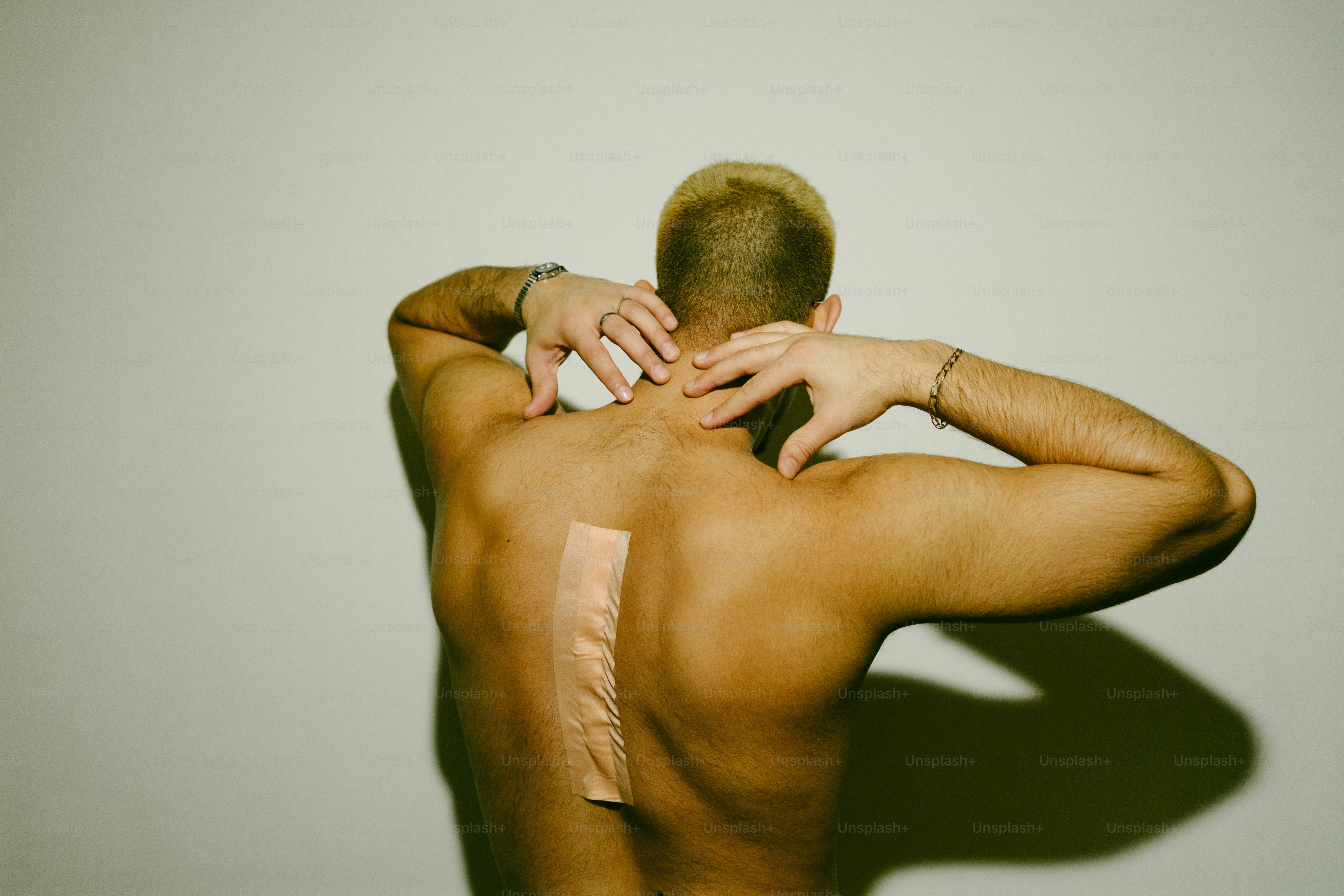 Homem com bandagem nas costas coçando o pescoço