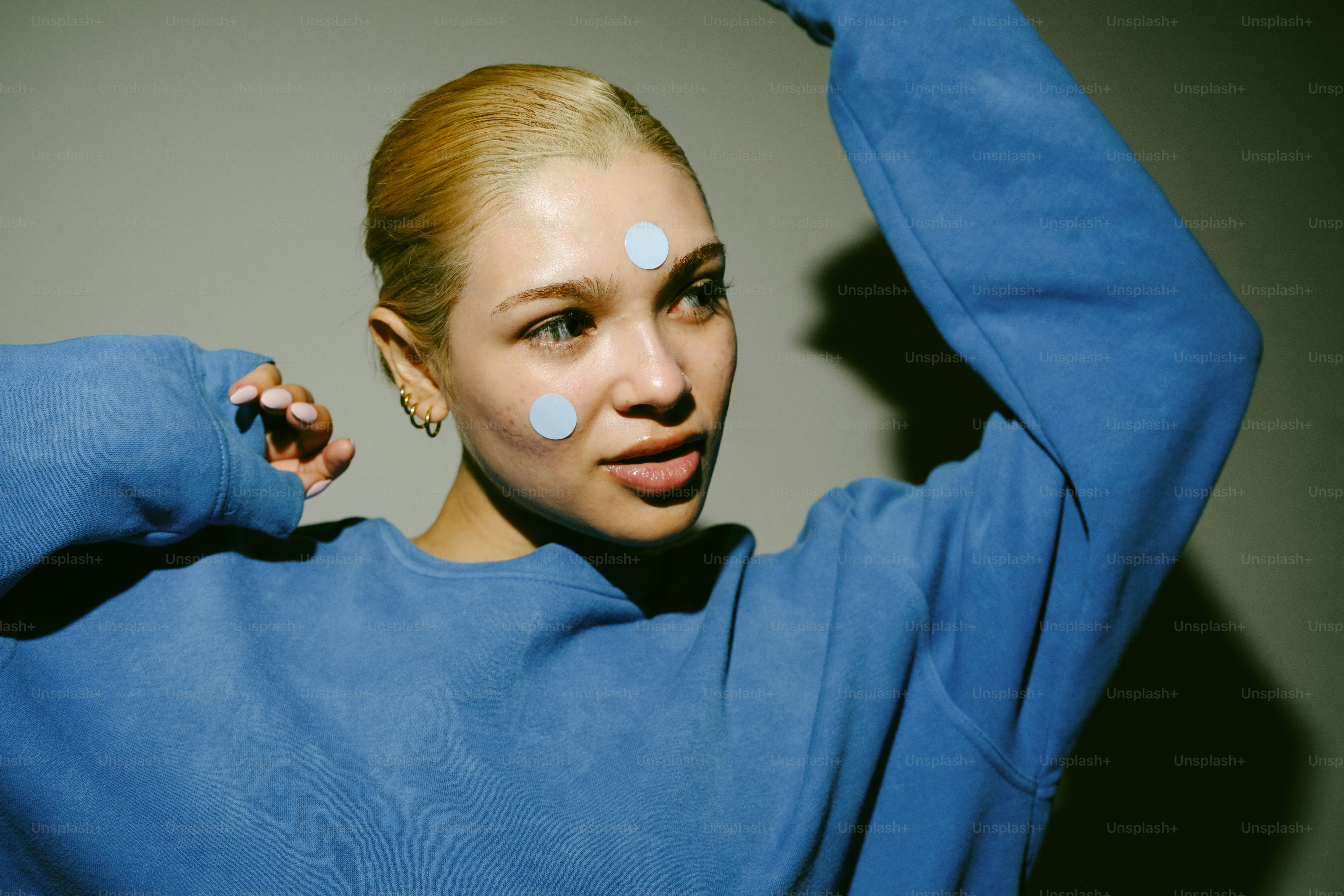 Mulher com pontos azuis no rosto usa moletom azul
