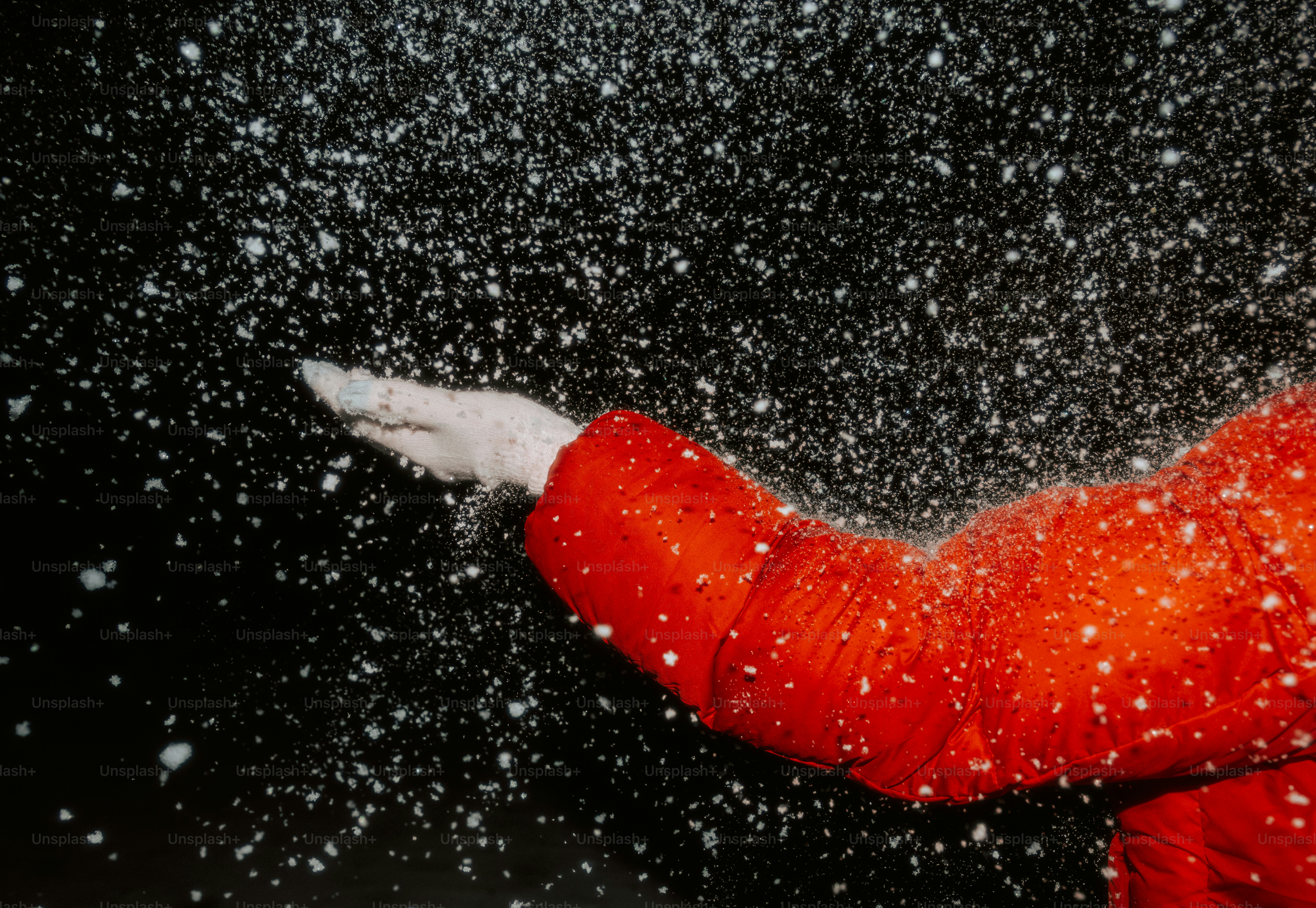 Hand catching falling snow in a red coat