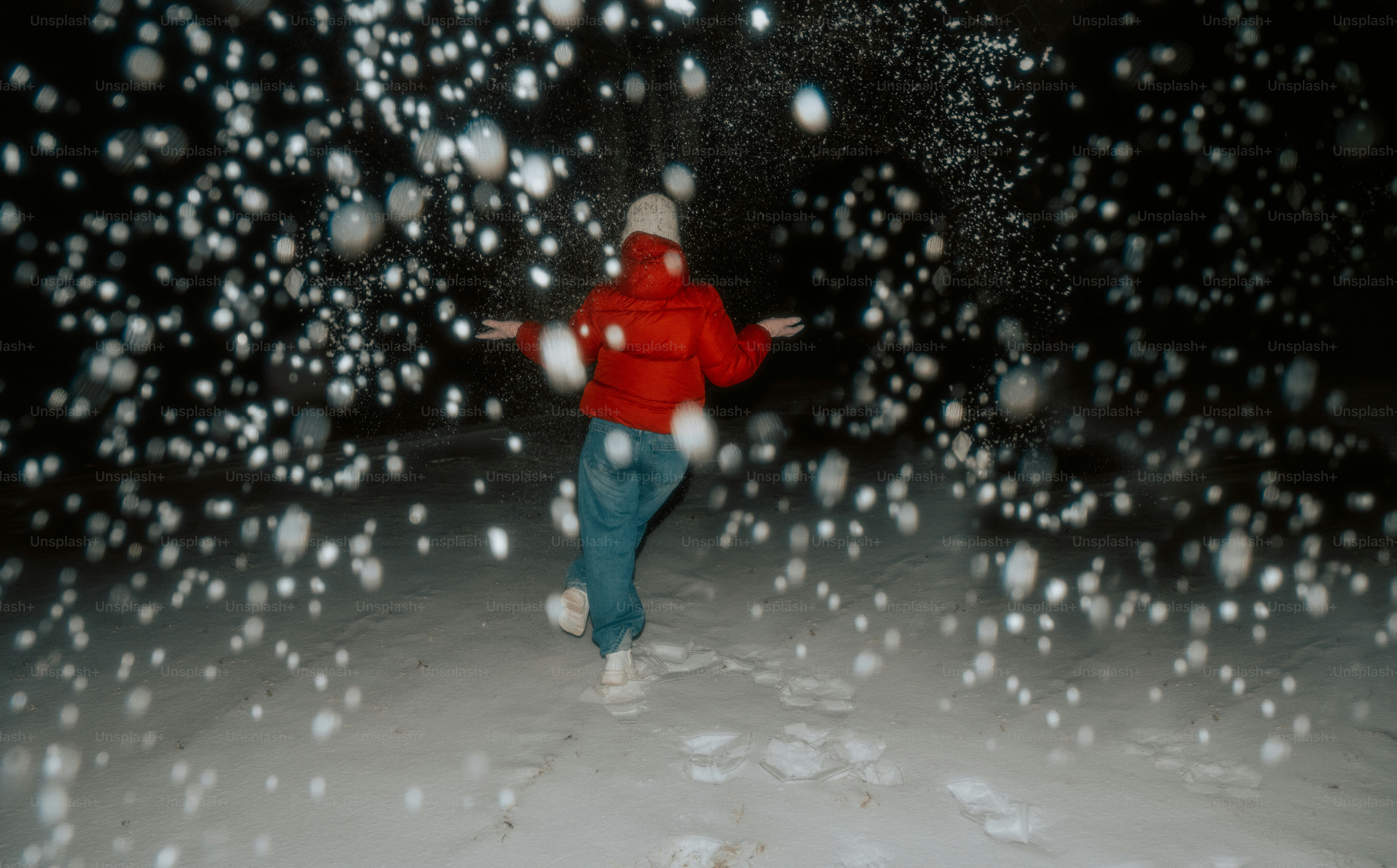 Person in red jacket dancing in falling snow