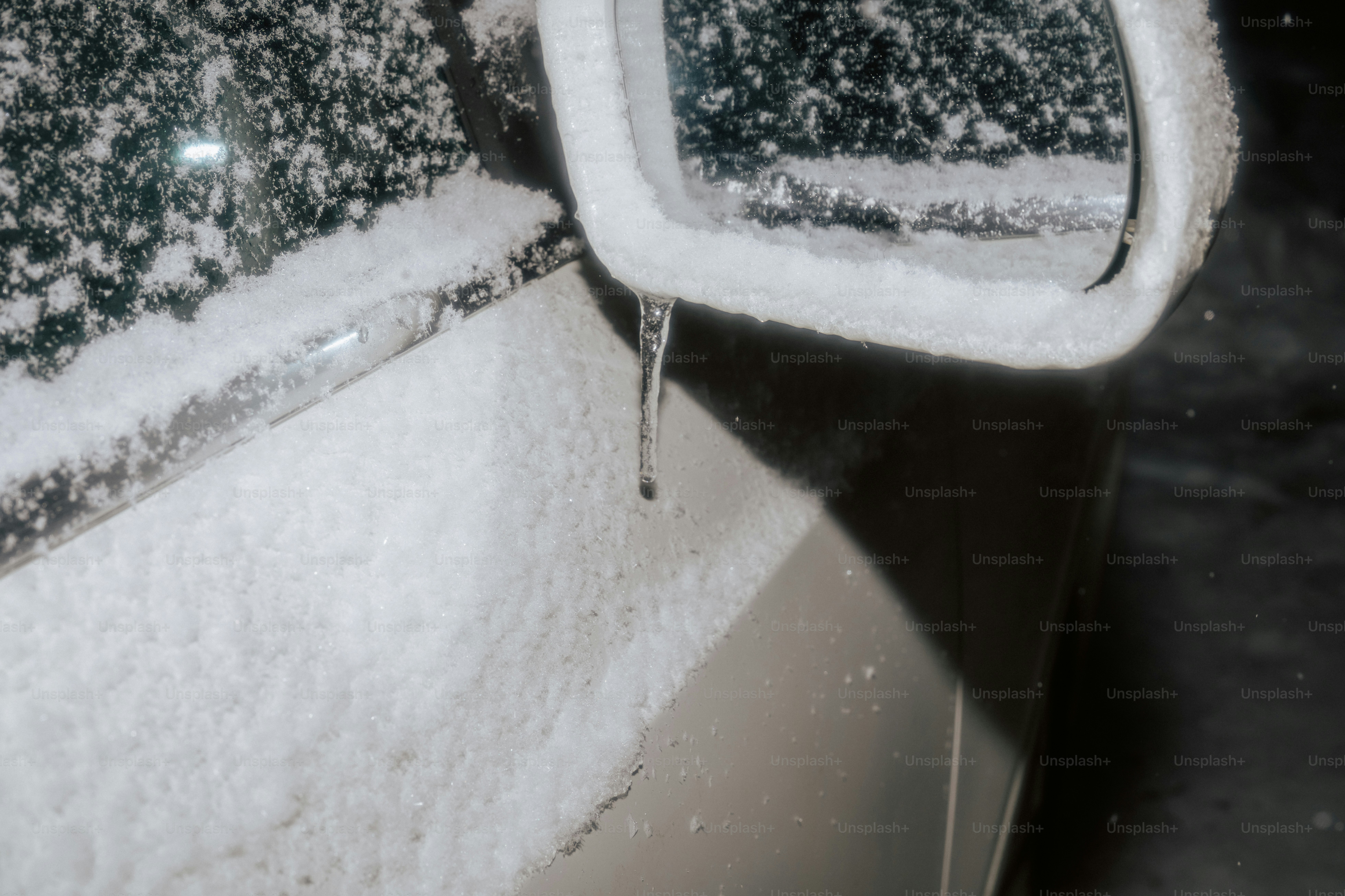 A car door and side mirror covered in snow