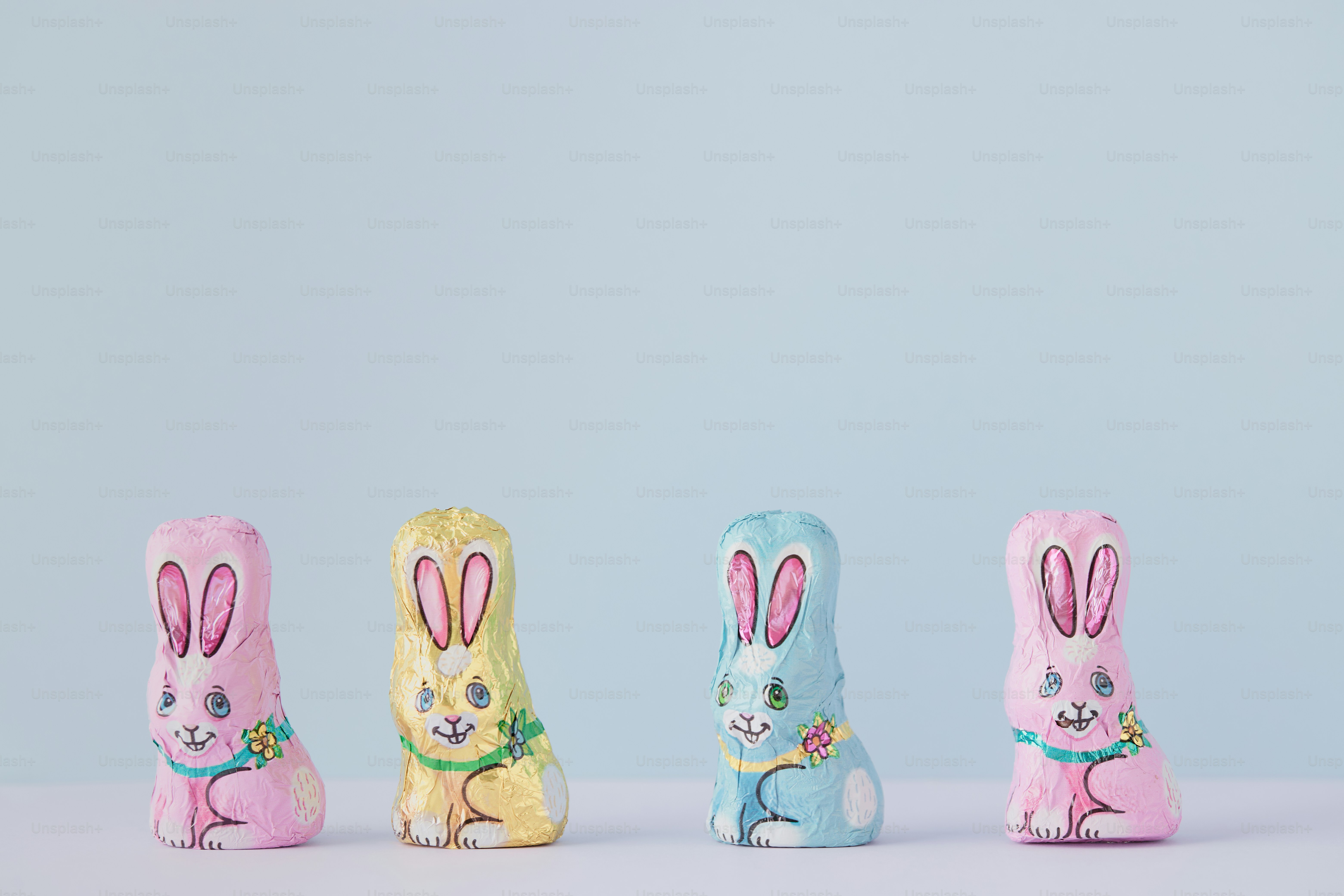 Four colorful chocolate bunnies on a pastel background