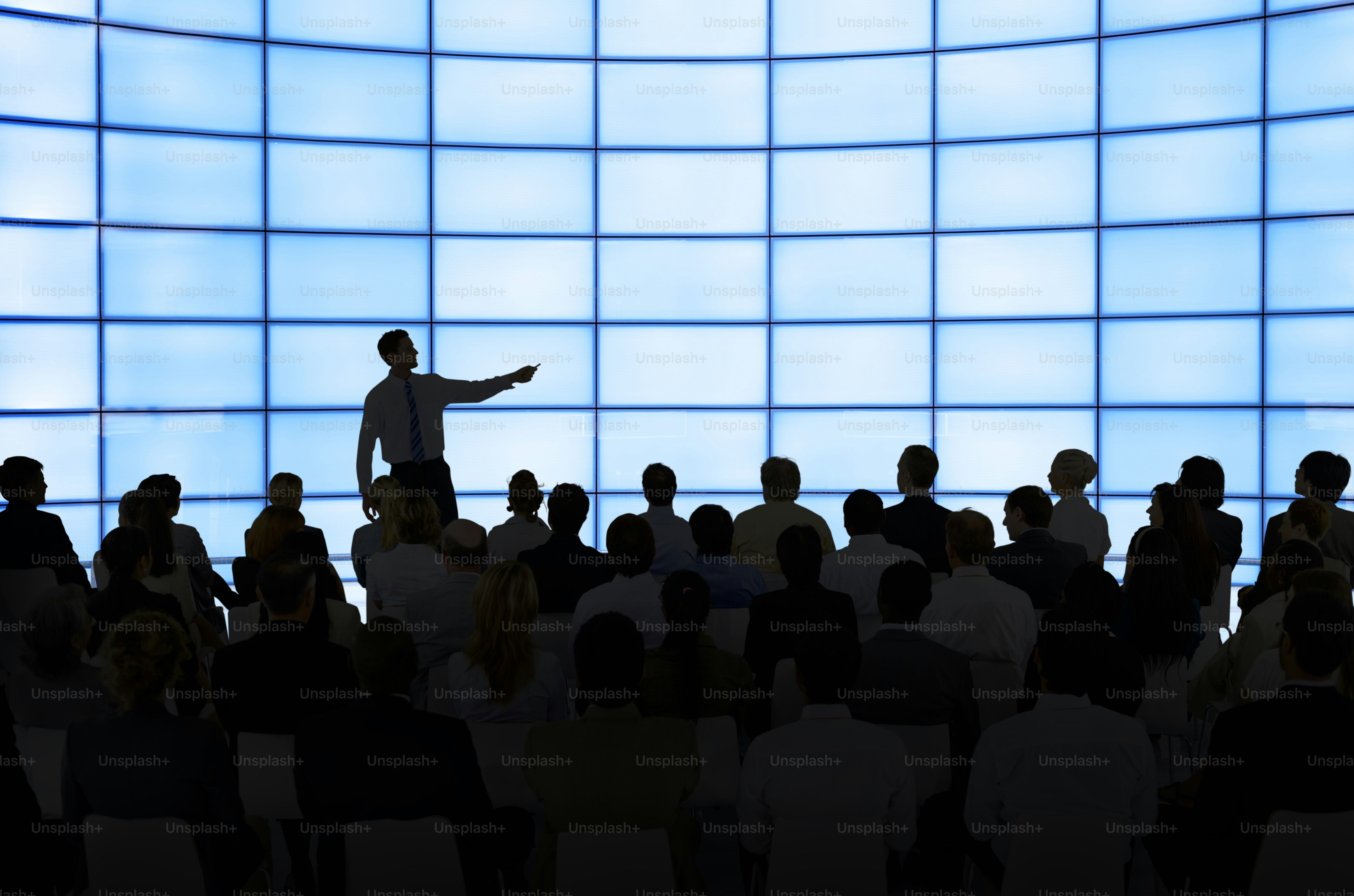 Redner spricht das Publikum vor einem blauen Raster-Hintergrund