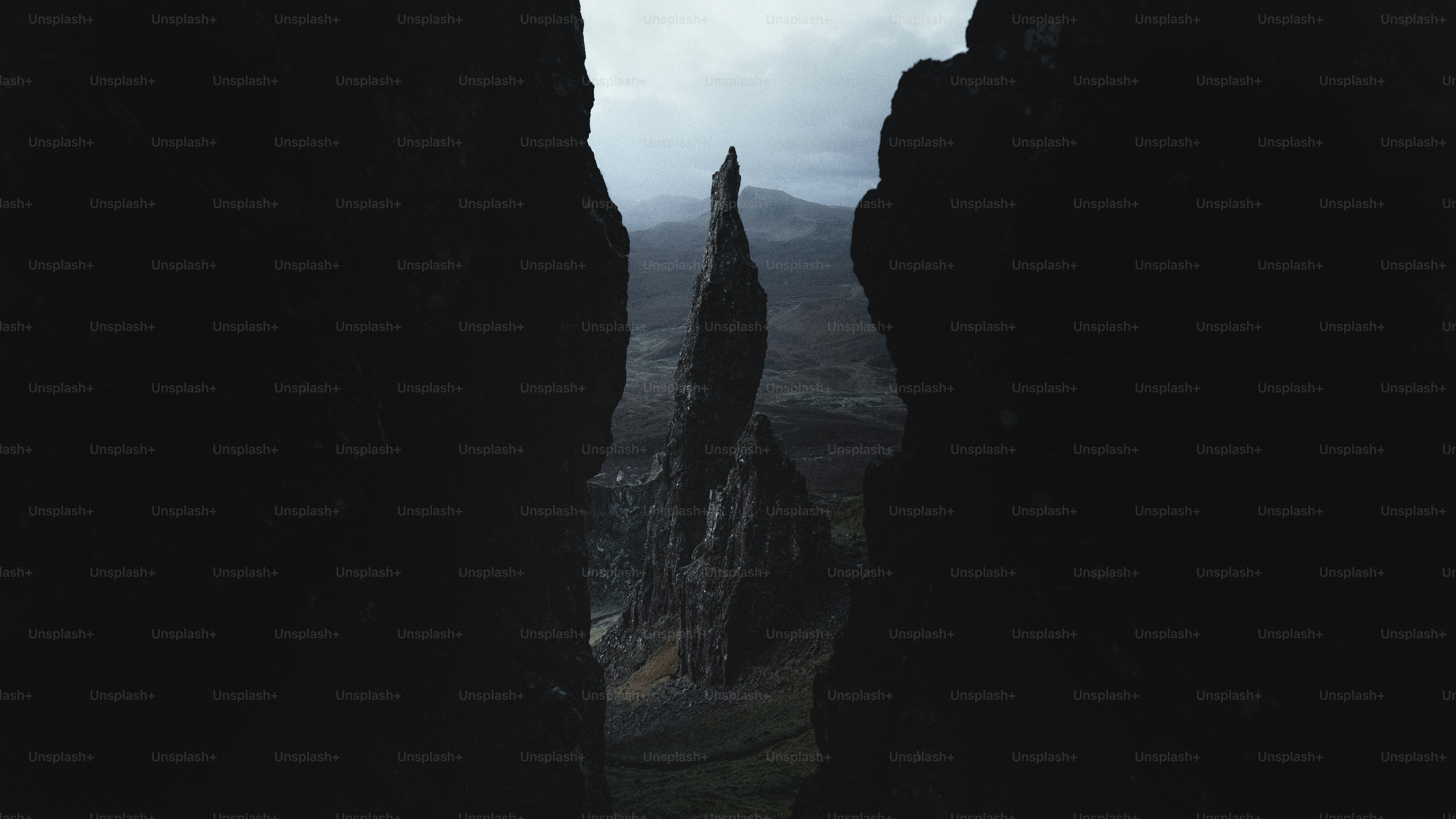 暗い崖の下草に囲まれた高い岩の尖塔