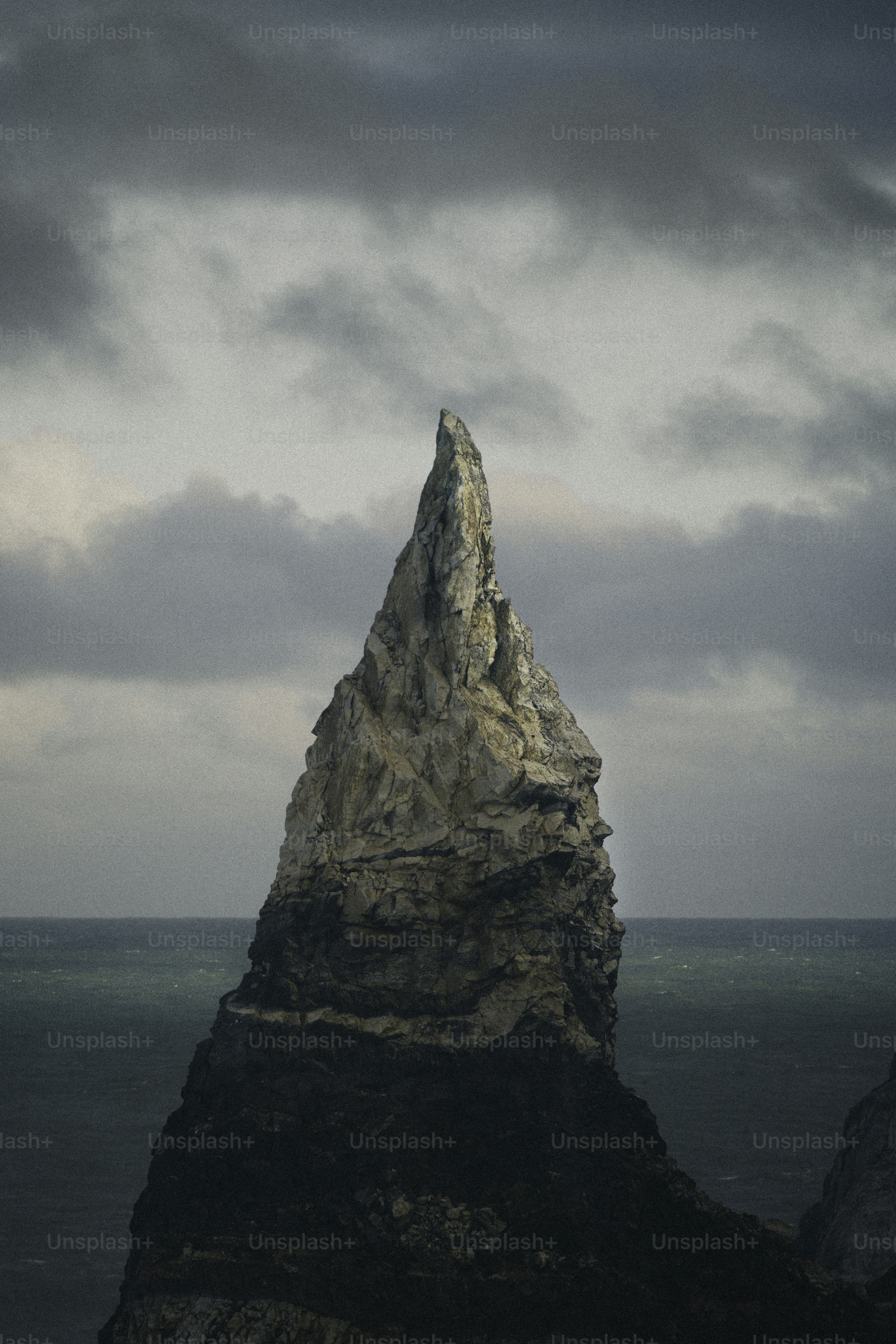 Gezackte Felsformationen, die sich unter wolkigem Himmel aus dem Meer erheben