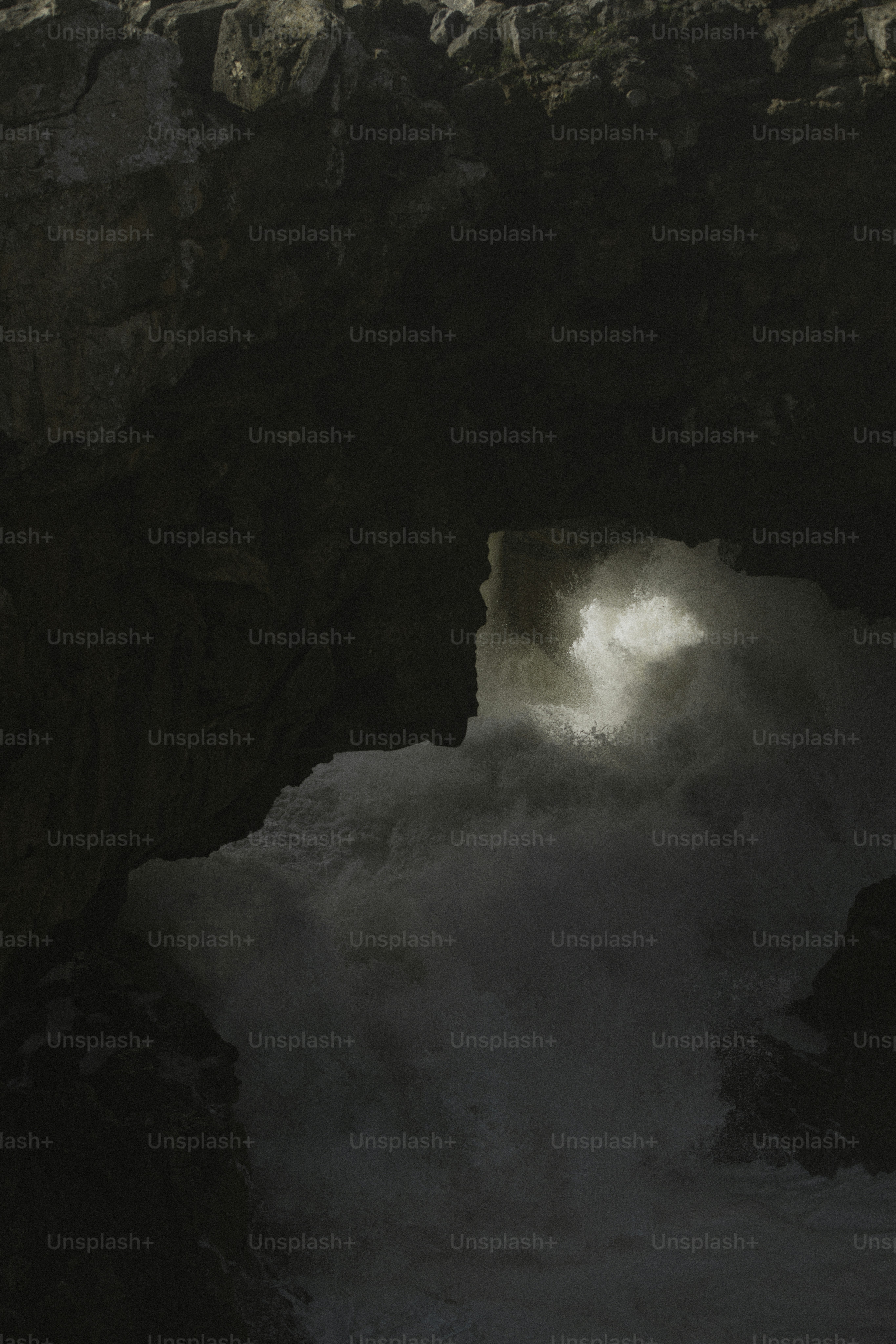 波が暗い岩の崖に打ち寄せ、明るい光を放ちます。