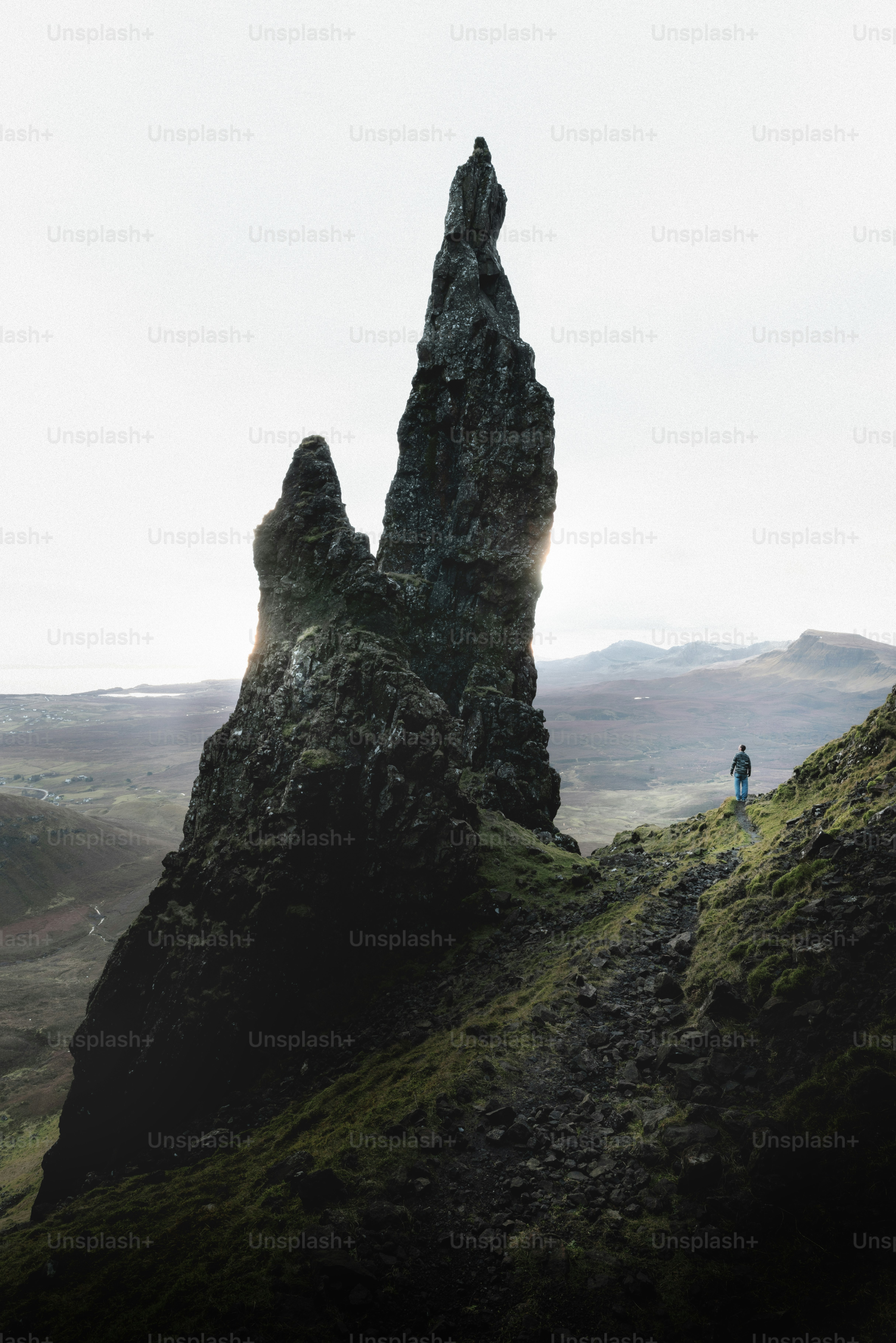 Ein einzelner Wanderer steht in der Nähe eines dramatischen Felsspitzens.