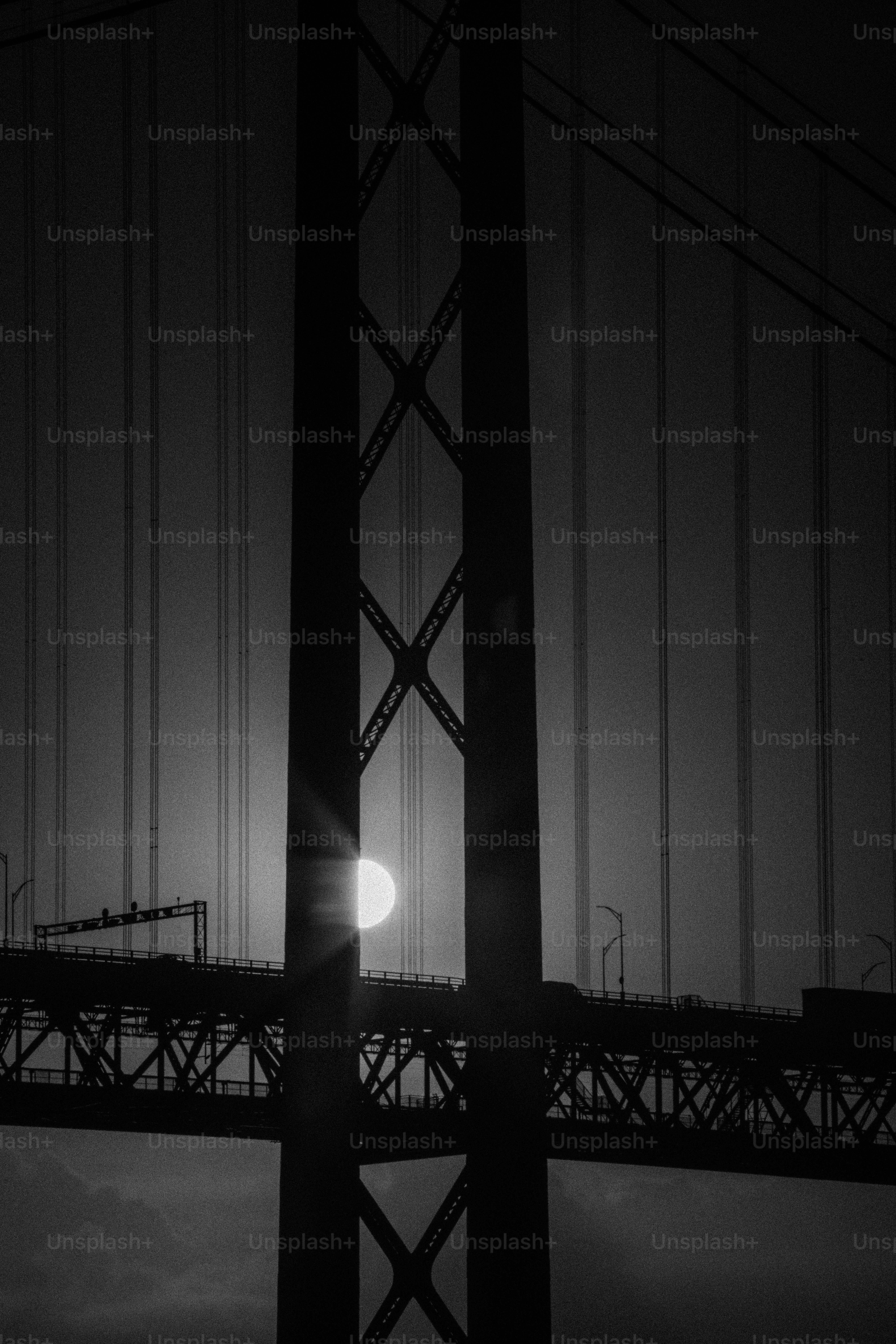 Die Sonne geht hinter einer Hängebrücke unter.