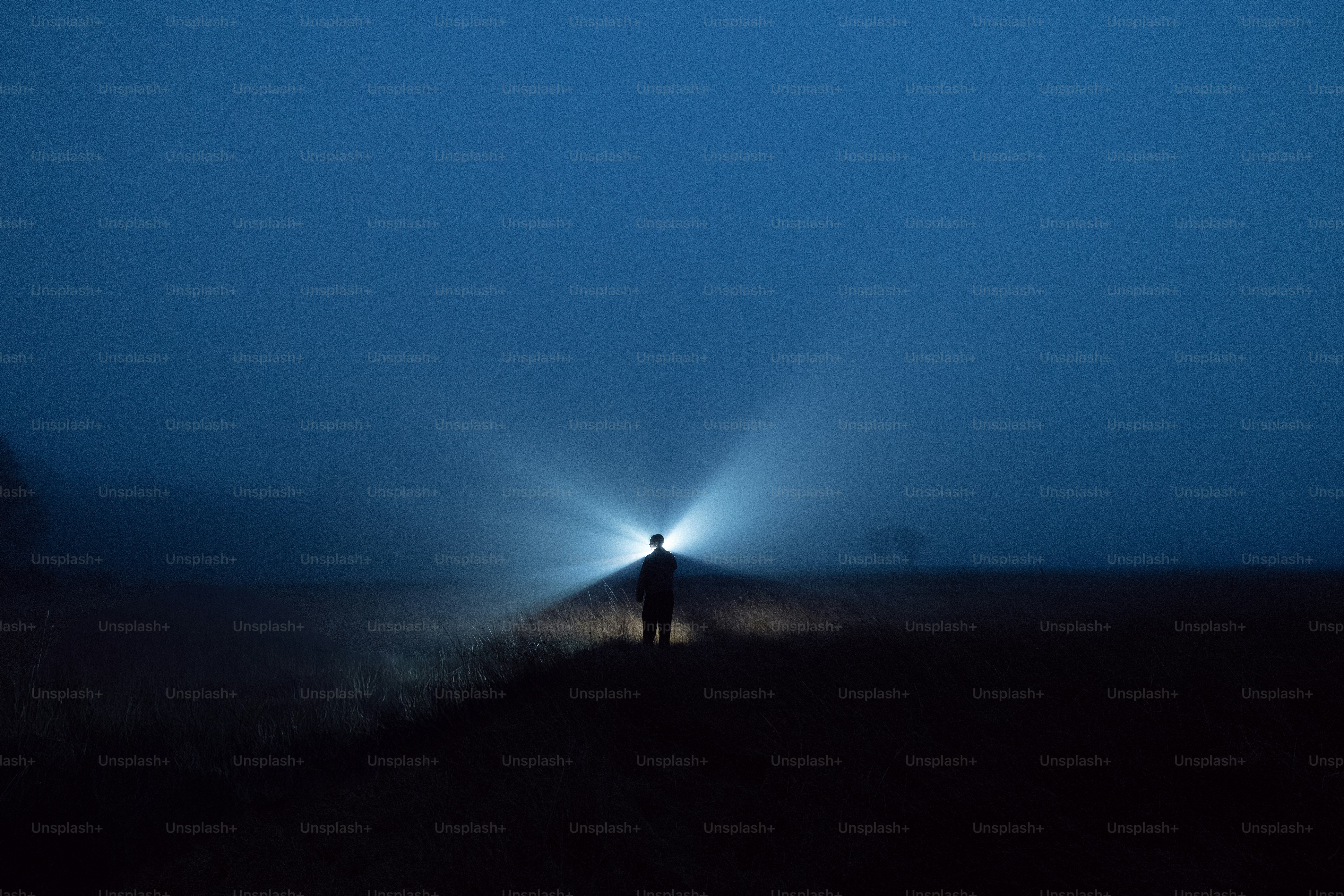 Une personne se tient dans le brouillard avec une lumière vive.