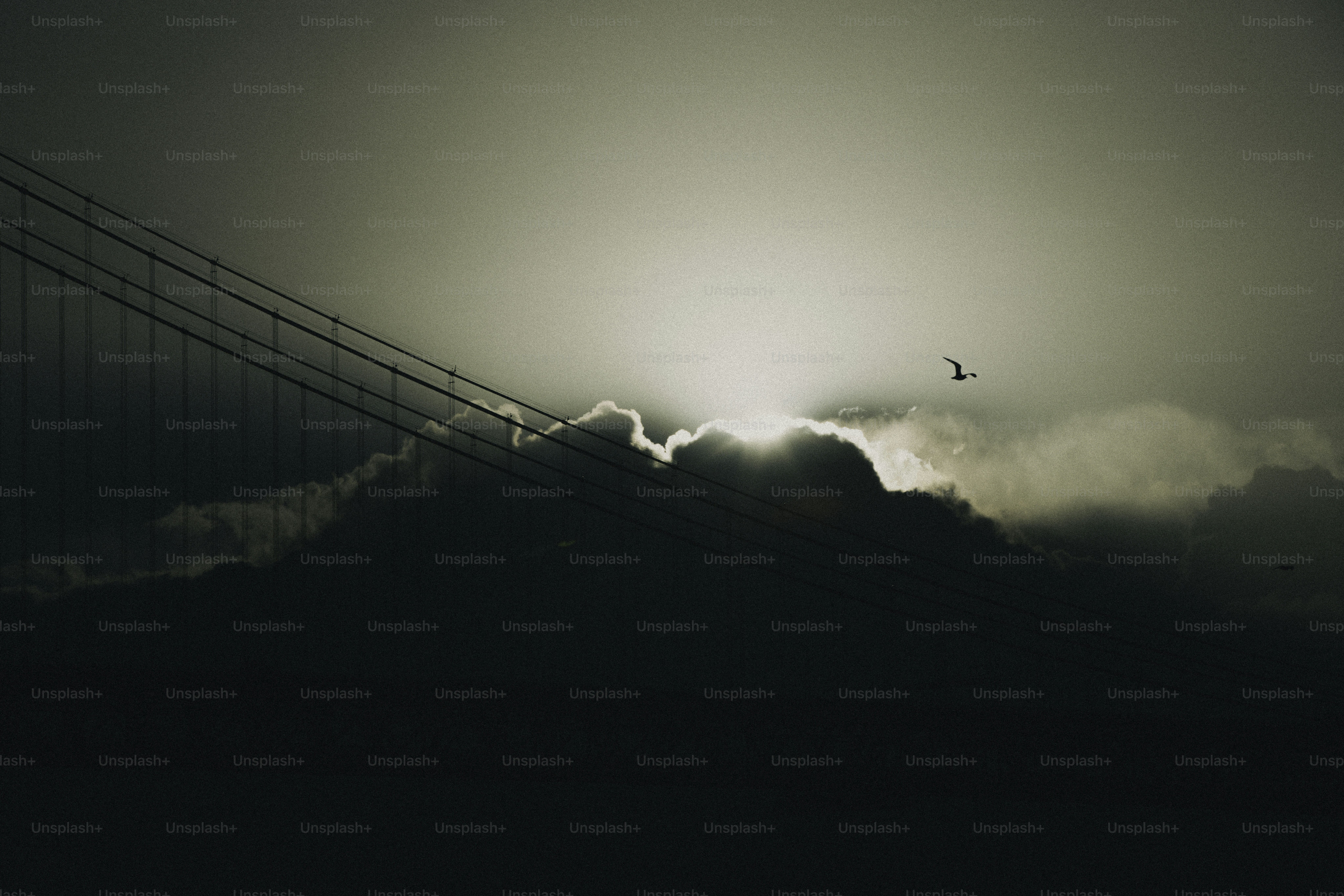 Sun setting behind clouds over a bridge