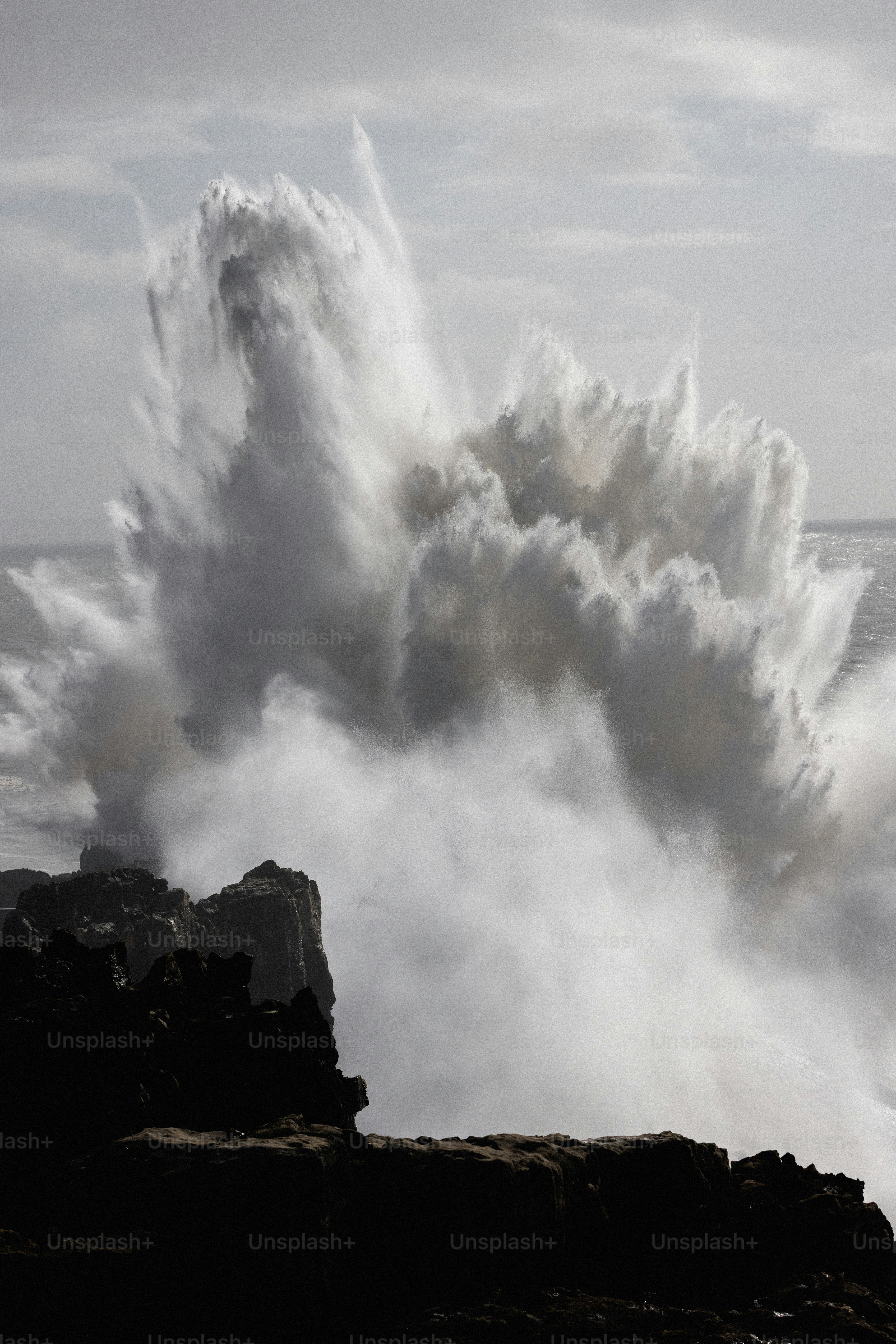 Mächtige Meereswellen, die gegen dunkle Felsen schlagen.