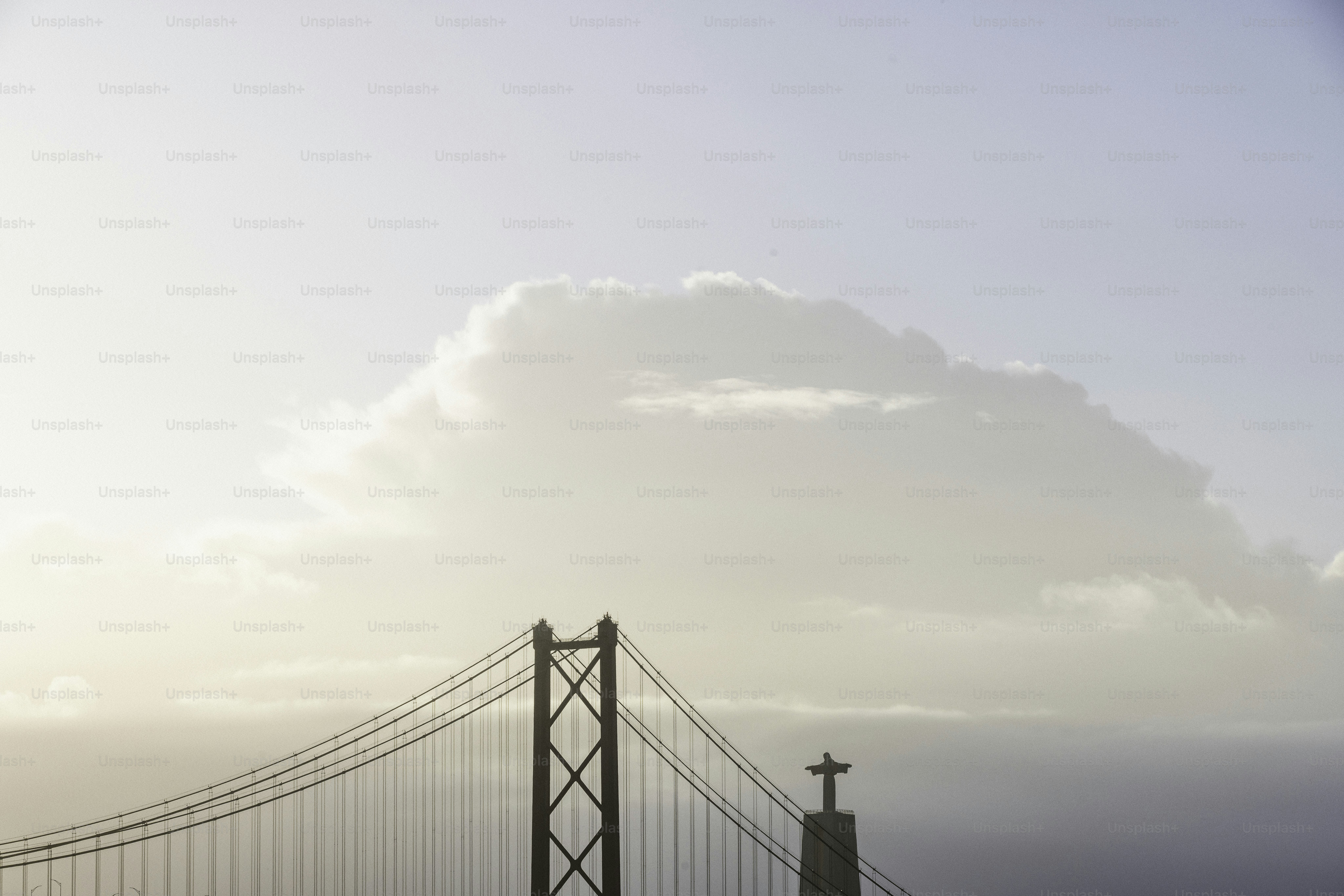Suspension bridge with a cross against a cloudy sky