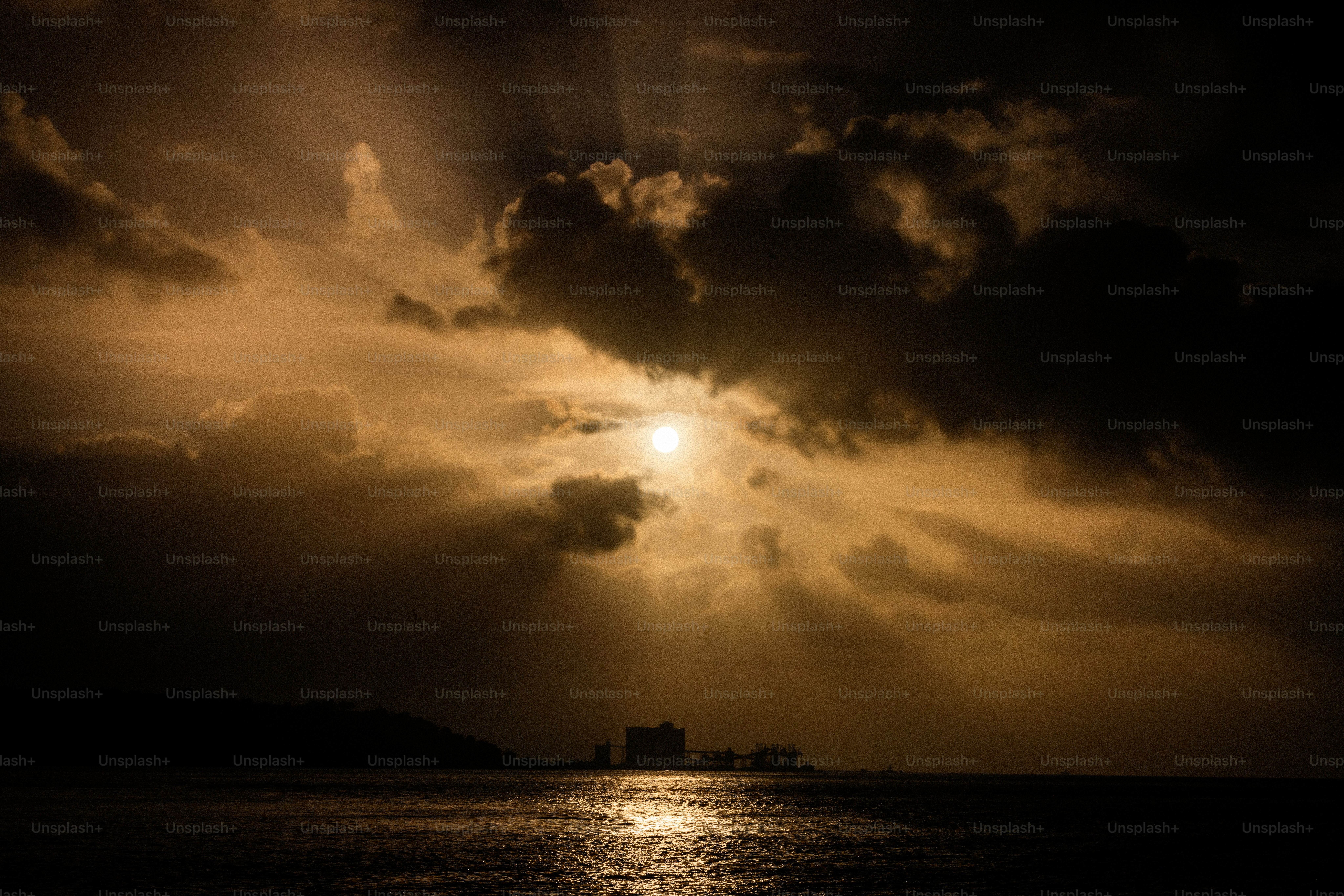 海に沈む劇的な夕焼けとシルエットの建物。