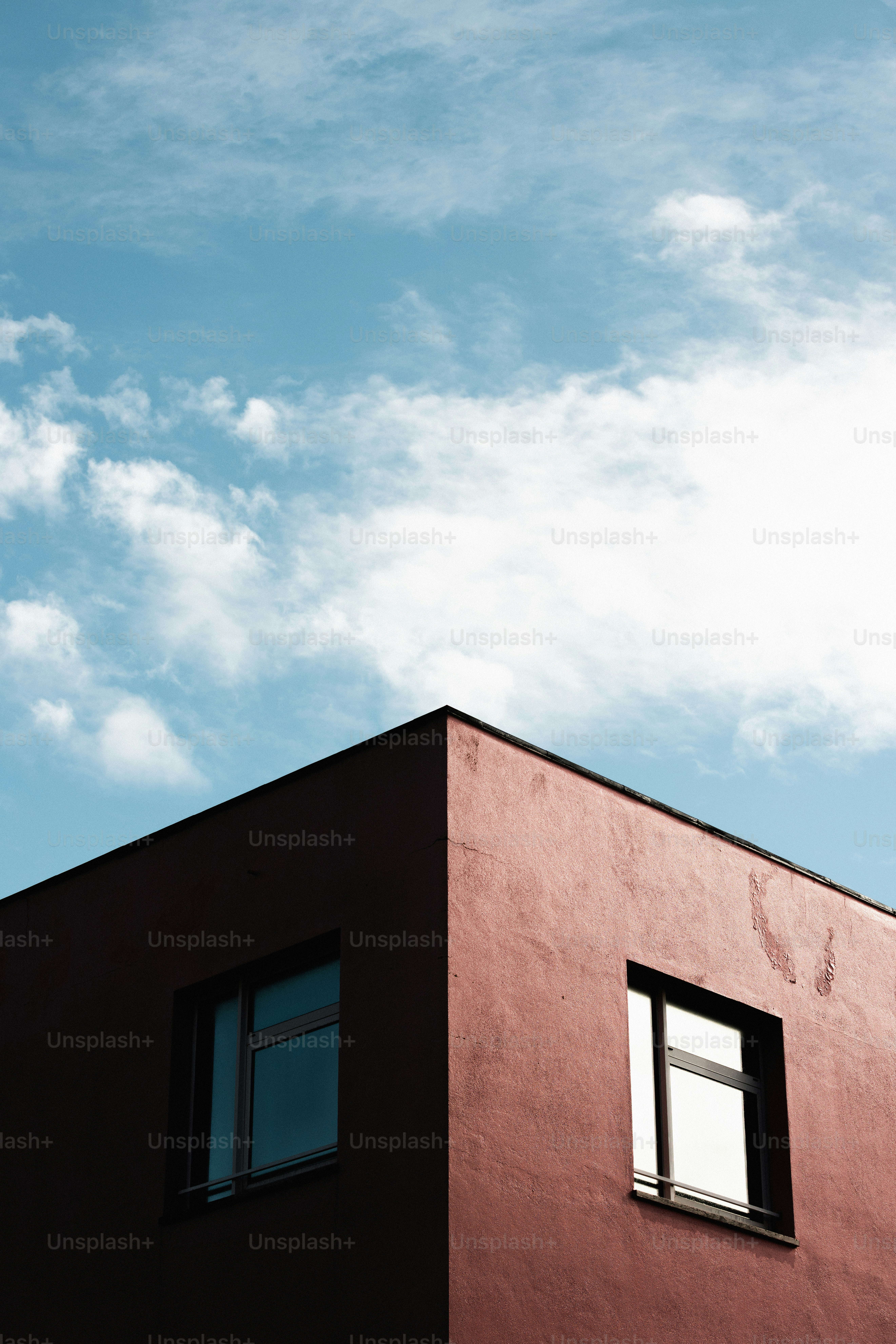 Corner of a red building against a cloudy blue sky