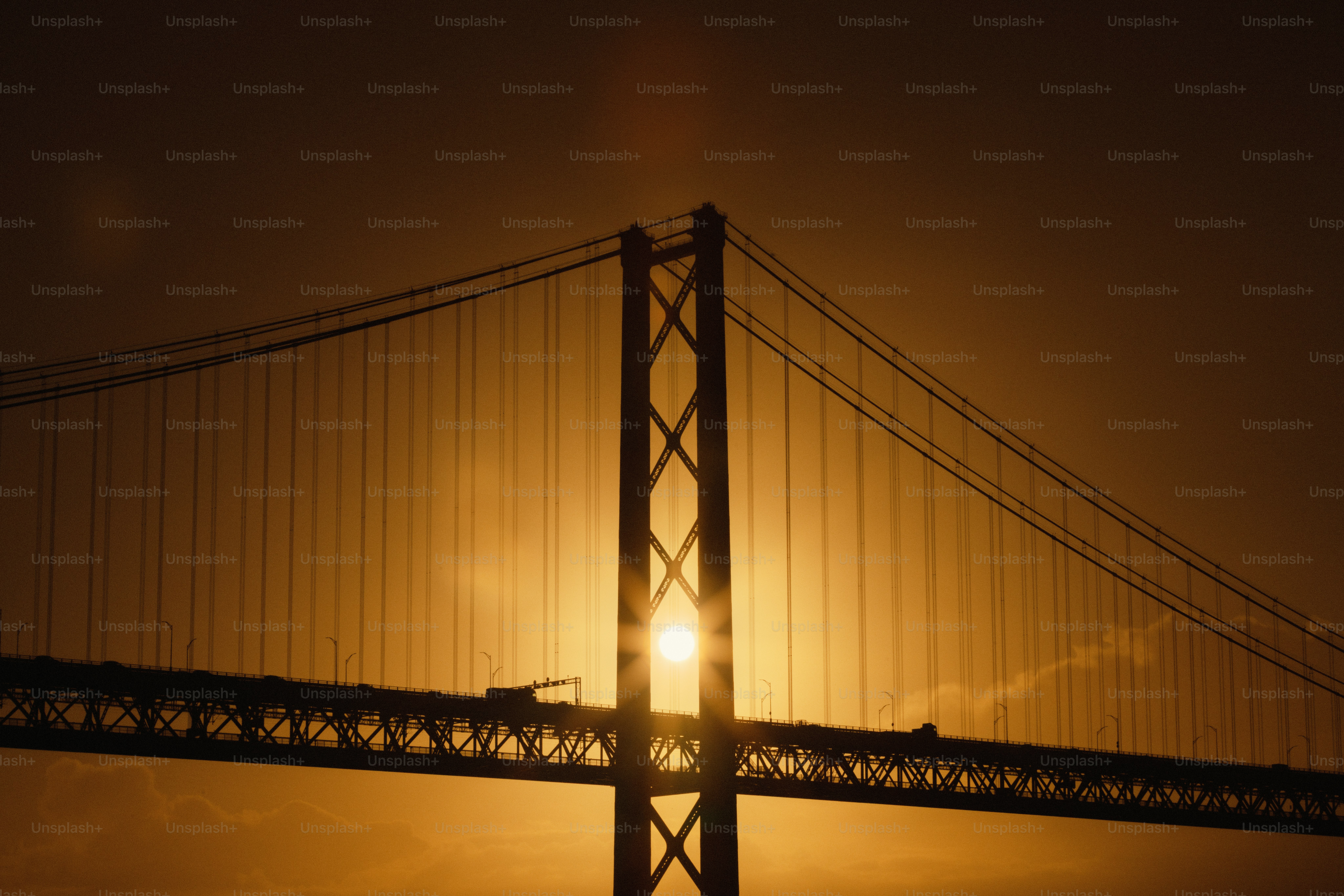 Suspension bridge silhouetted against a golden sunset photo – Travel ...