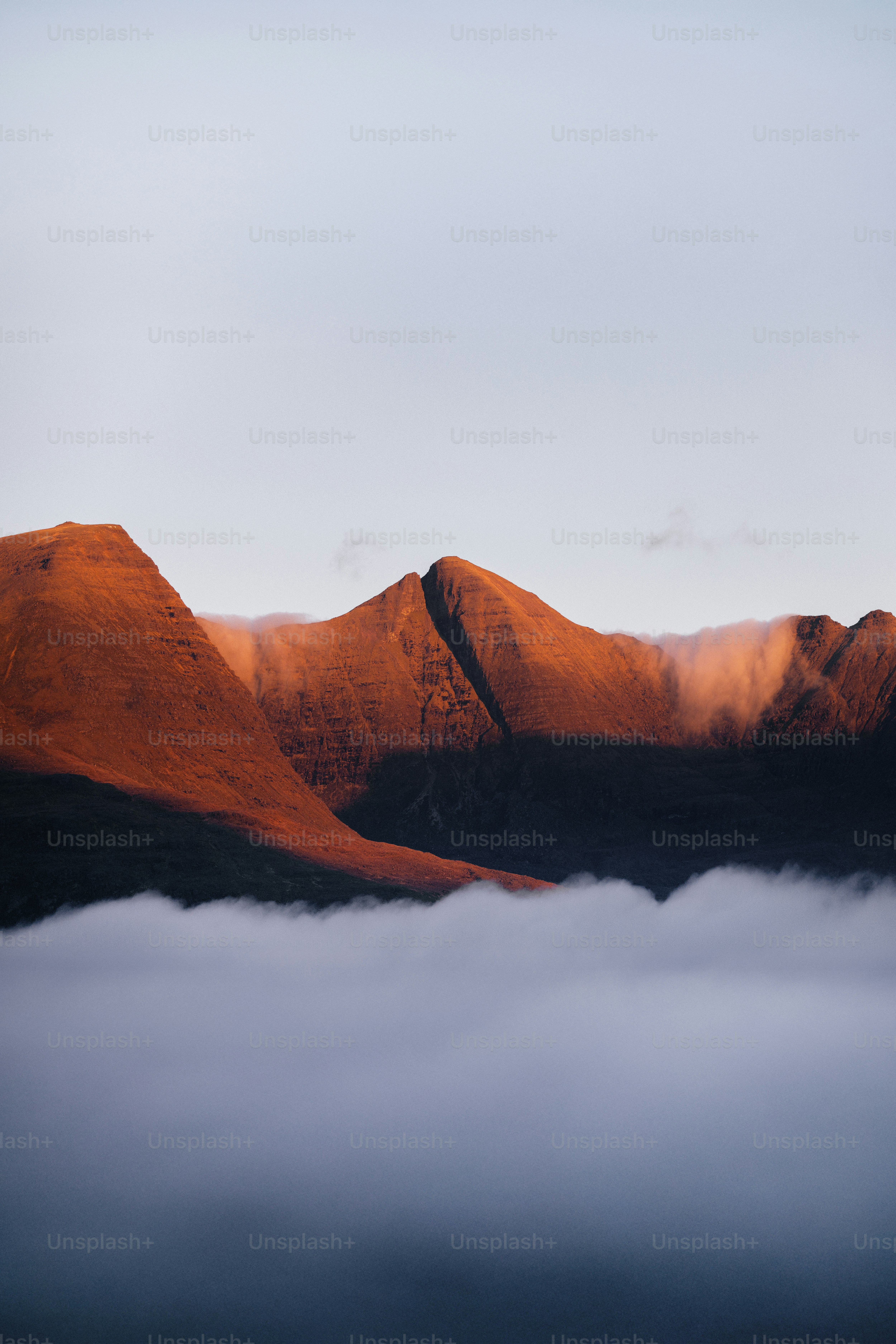 Mountain peaks illuminated by golden hour sunlight above clouds.