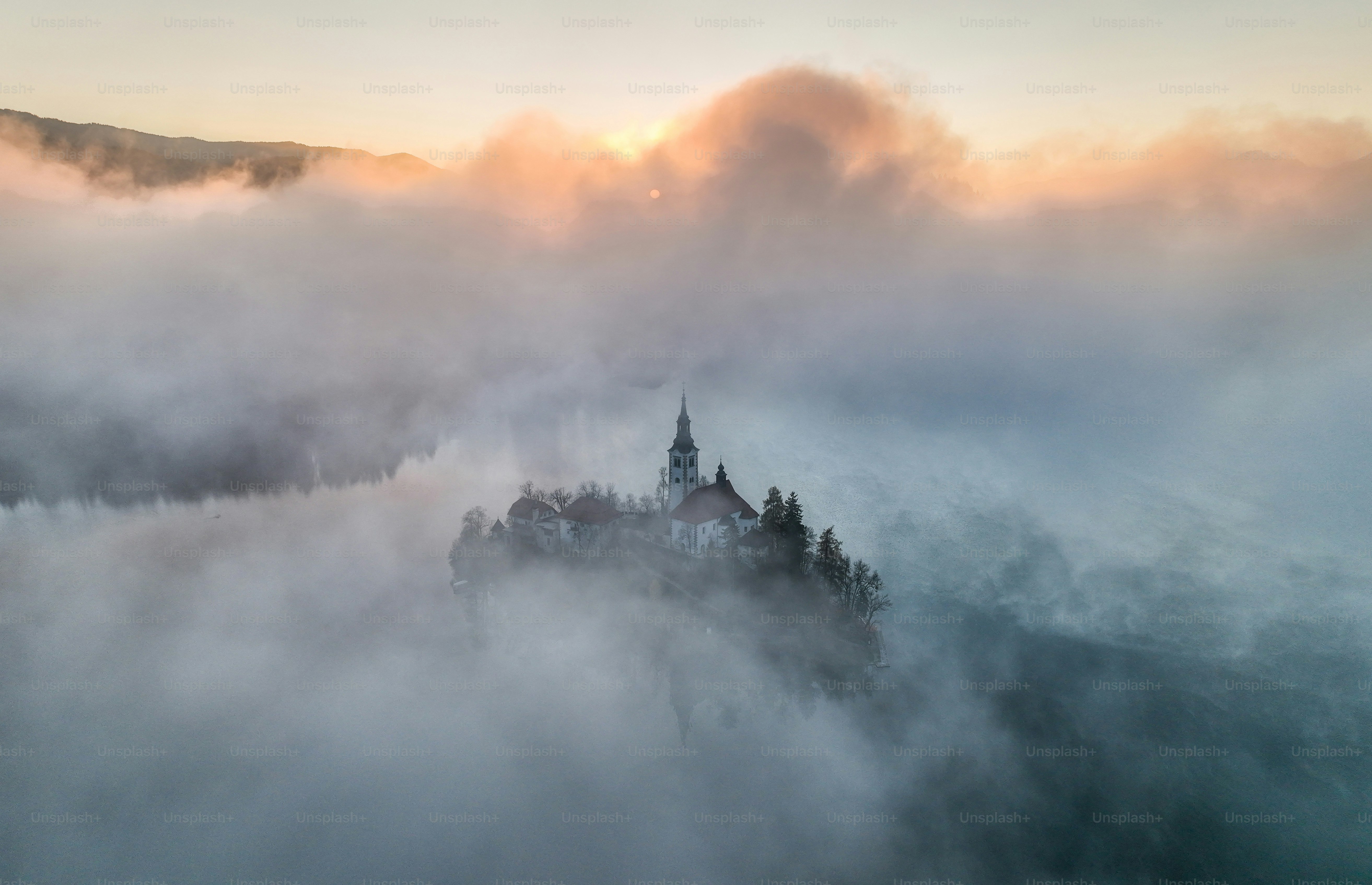 Der Kirchturm taucht bei Sonnenaufgang aus nebligen Wolken auf.
