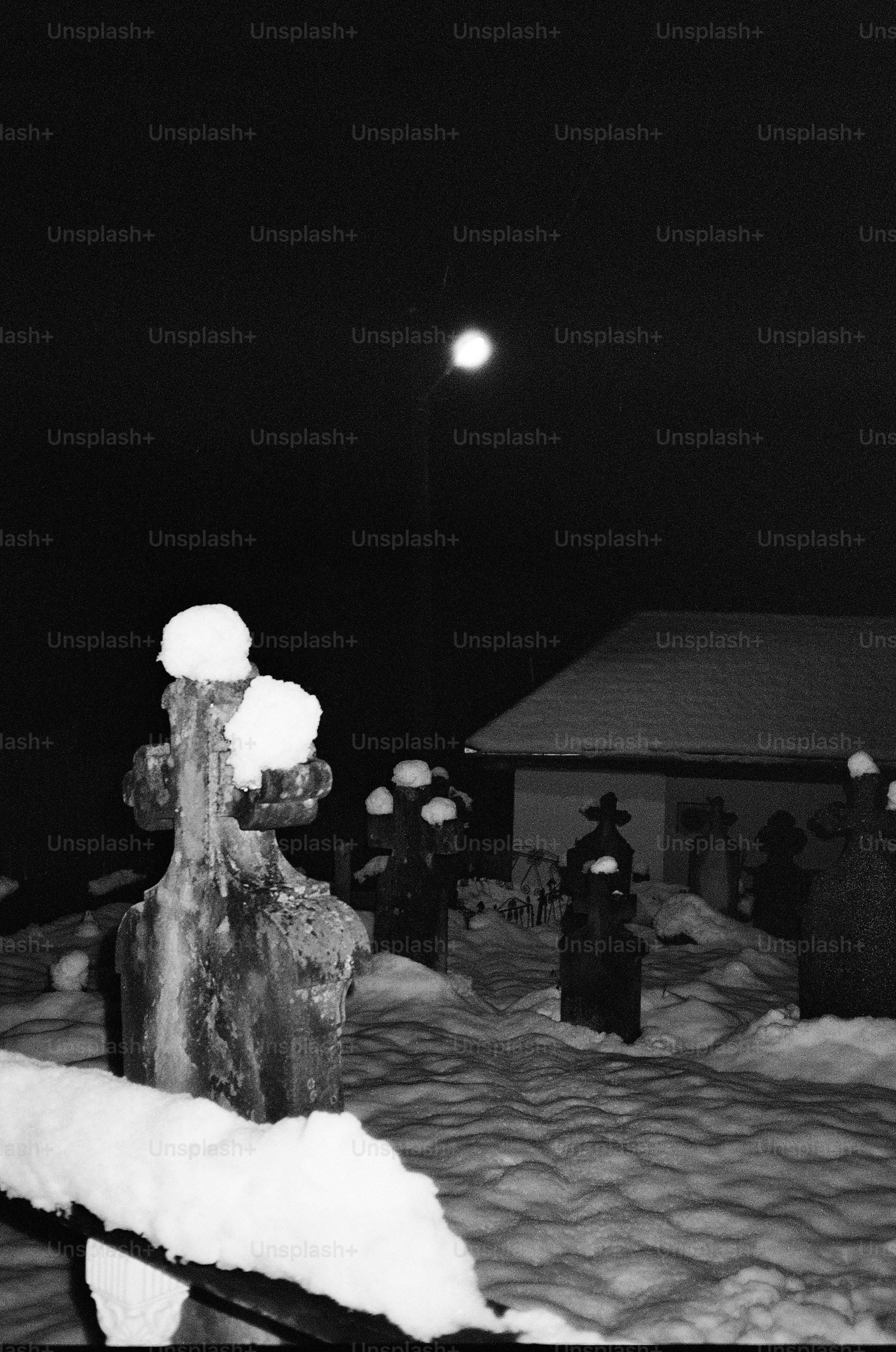 Schneebedeckte Grabsteine auf einem Friedhof bei Nacht